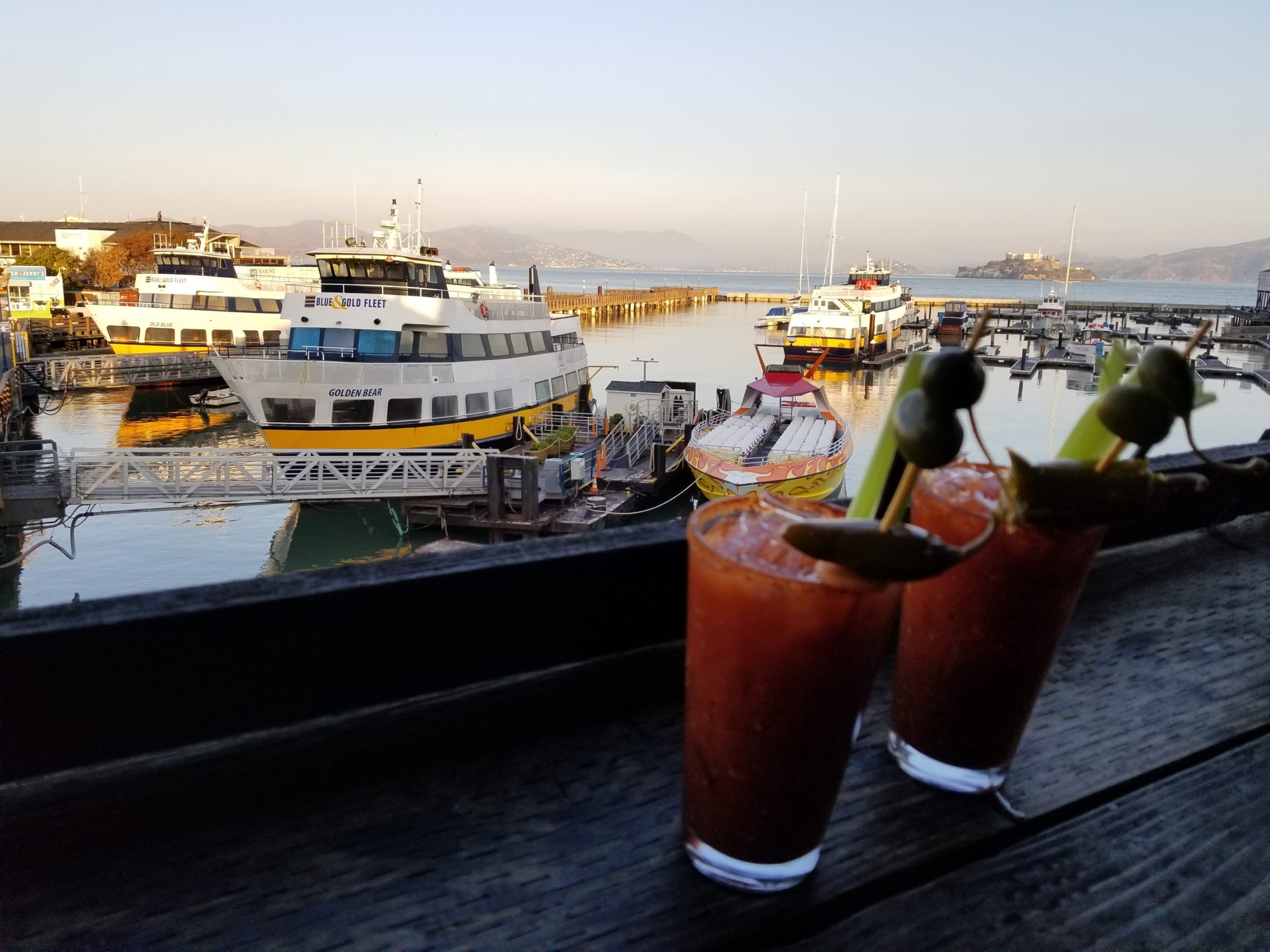 two glasses of drinks on a table with boats in the background