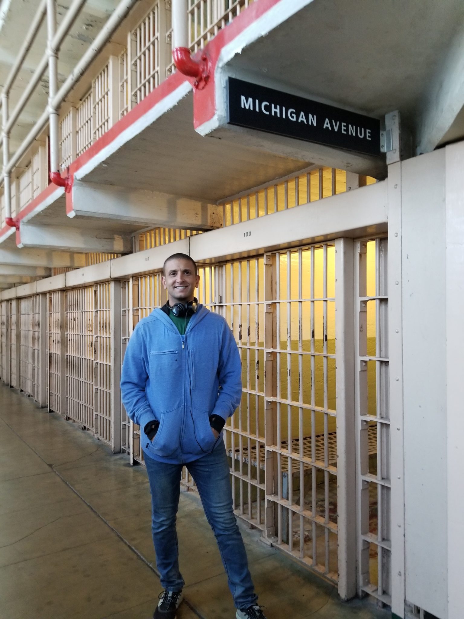 a man standing in a hallway with bars and a sign