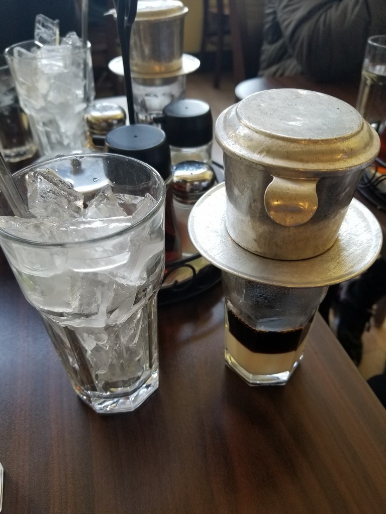 a glass of ice and a metal container on a table