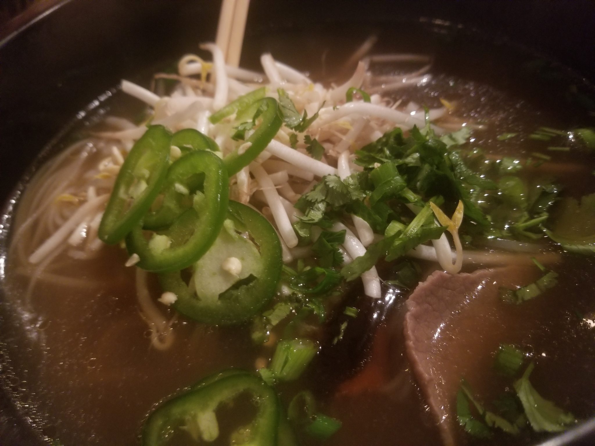 a bowl of soup with meat and jalapenos