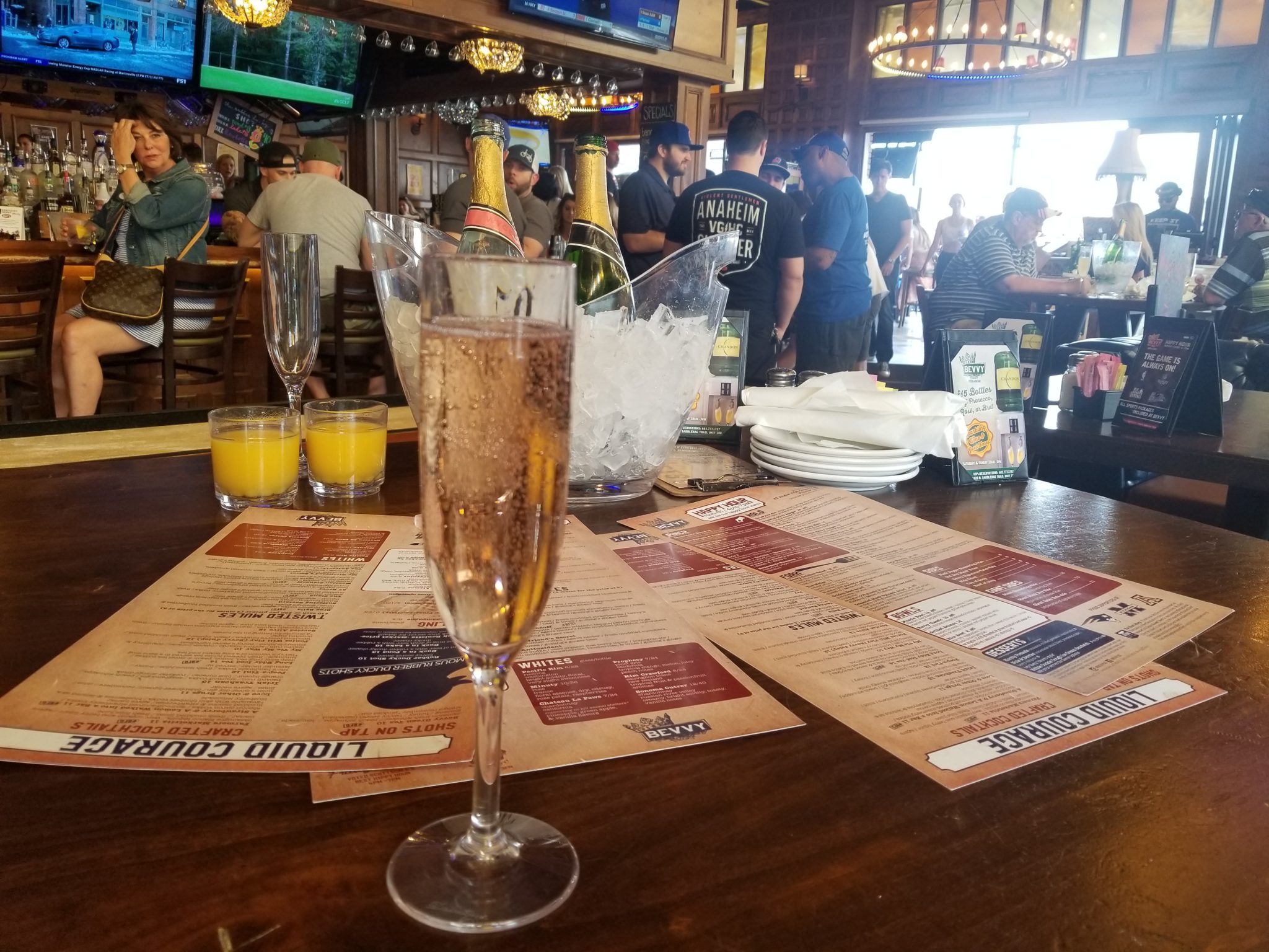 a glass of champagne on a table with drinks and menus