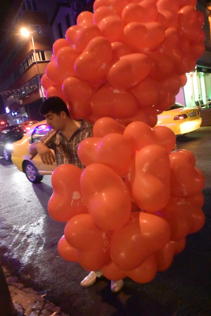 a man standing in front of a large bunch of balloons