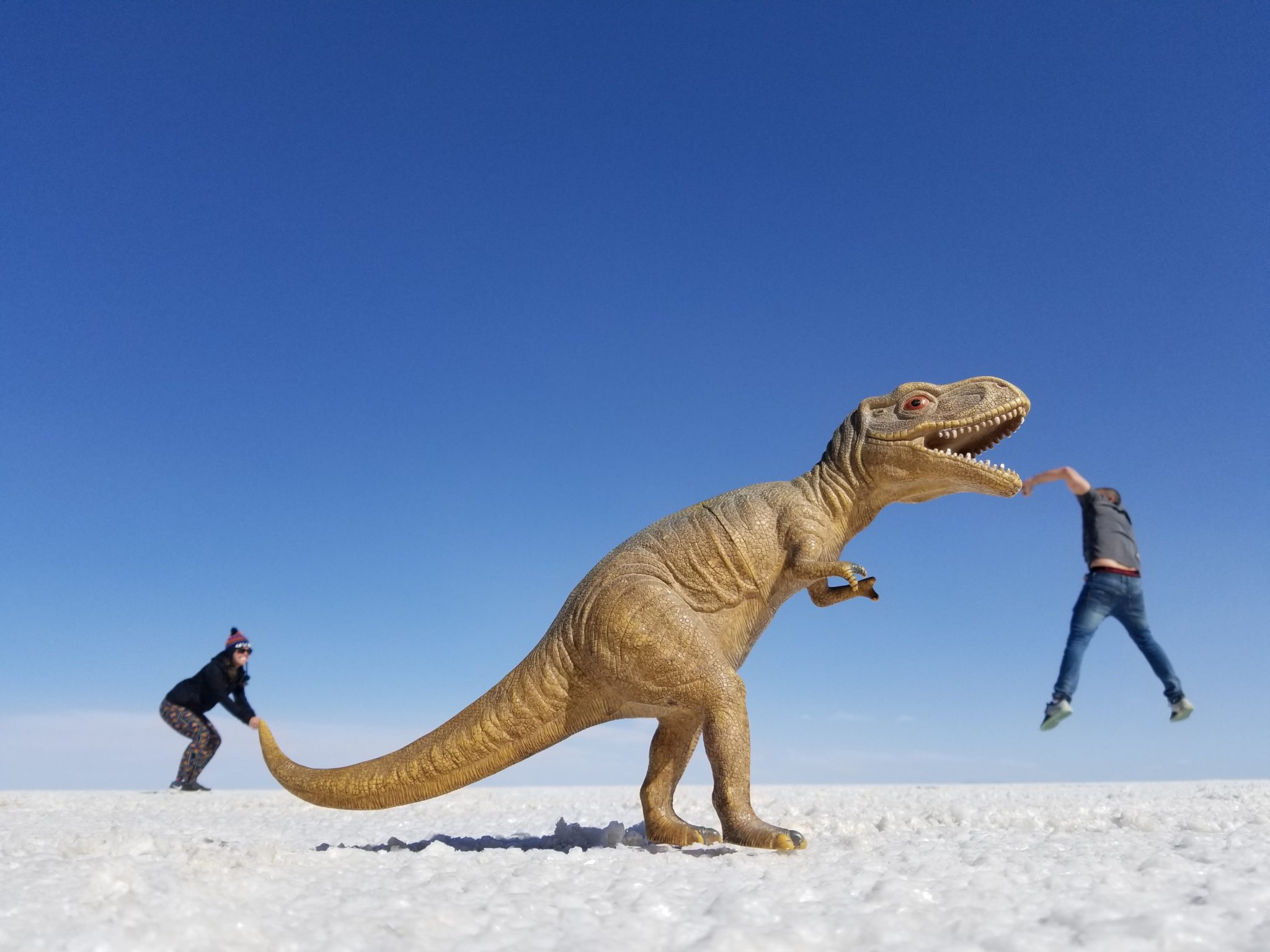 a dinosaur toy with a person running away from it