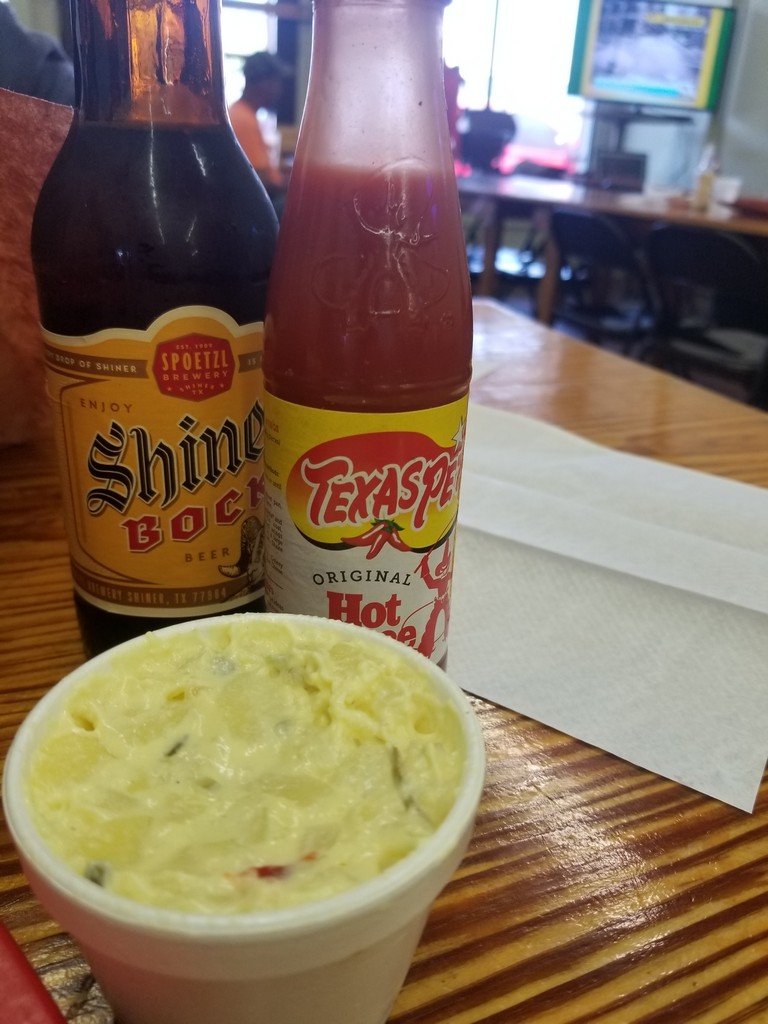 a bowl of dip and a bottle of hot sauce on a table