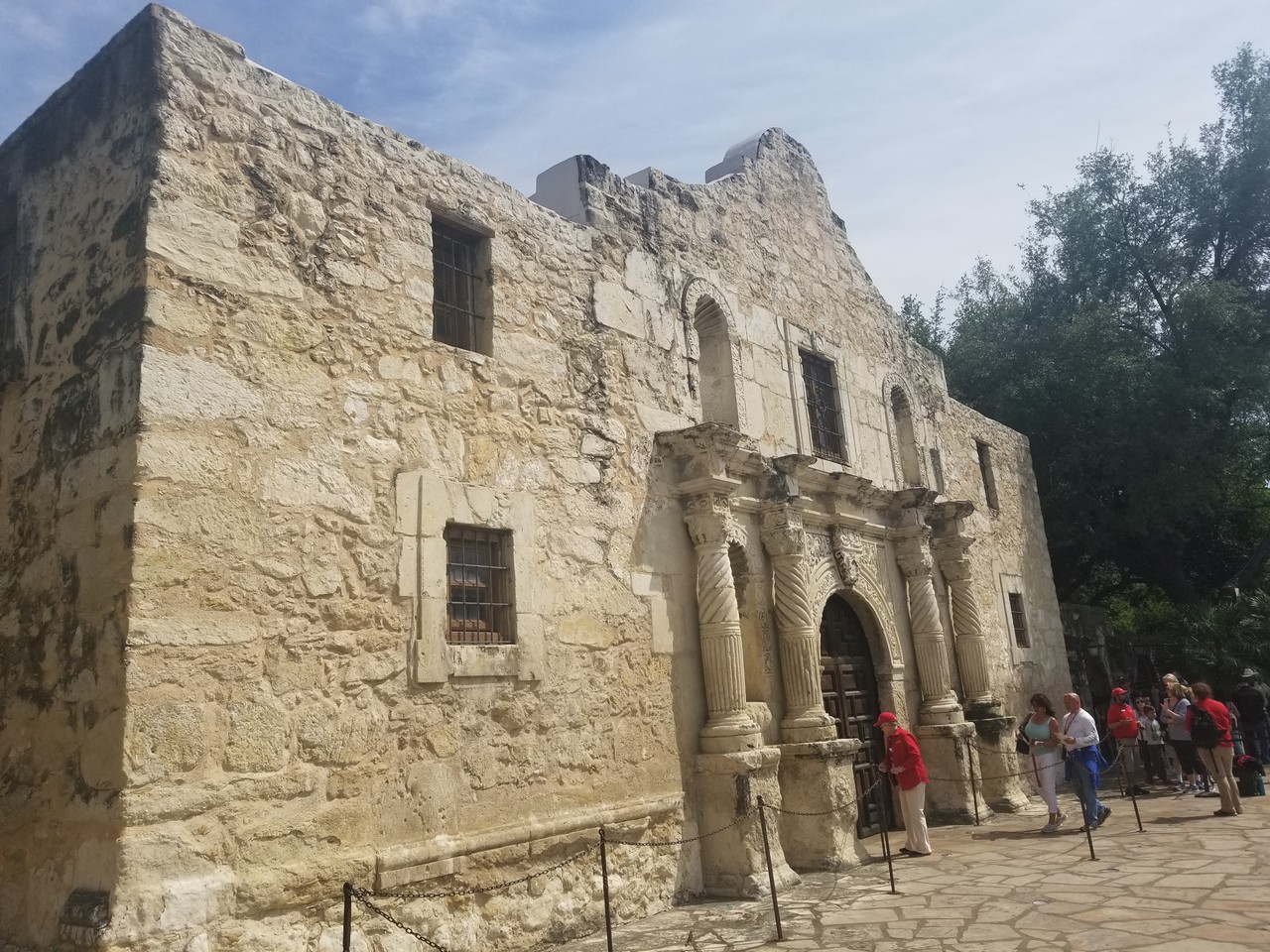 people walking around a stone building with Alamo Mission in San Antonio in the background