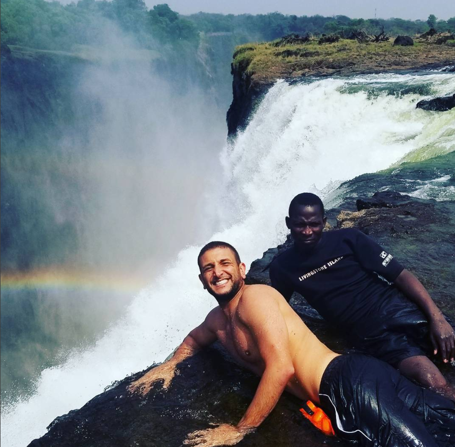 two men posing for a picture in front of a waterfall