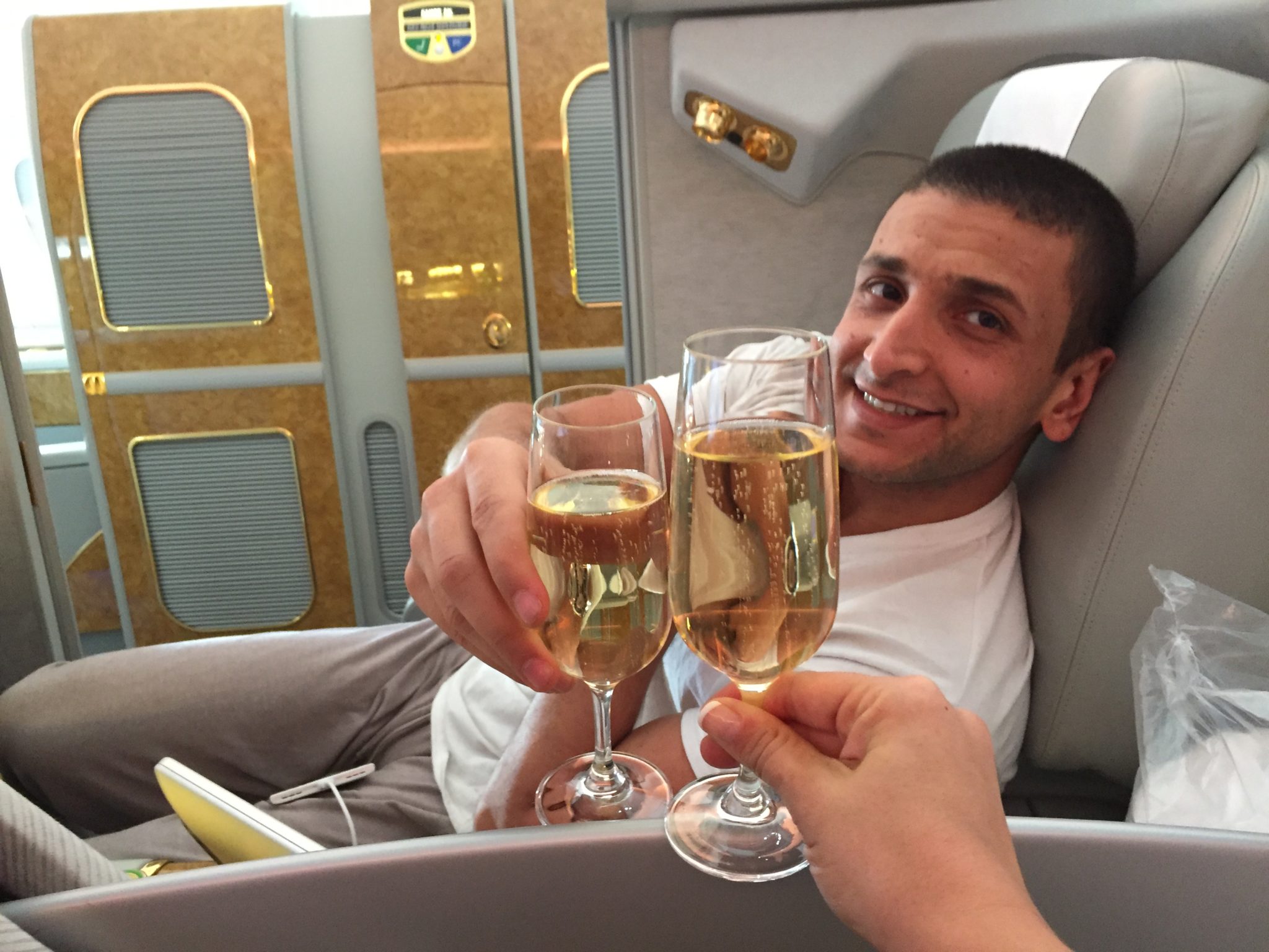 a man holding wine glasses in a plane