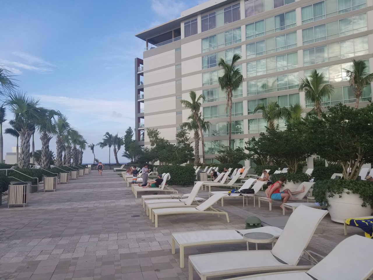 a group of people sitting on lounge chairs outside of a hotel