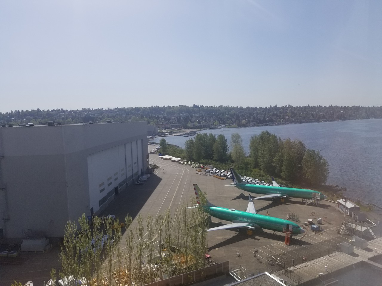 a group of airplanes parked on a parking lot next to a body of water