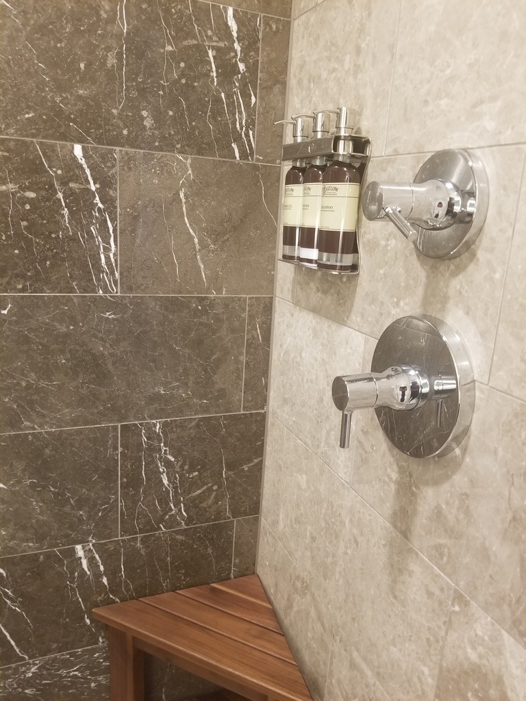 a shower with soap dispensers and a tile wall