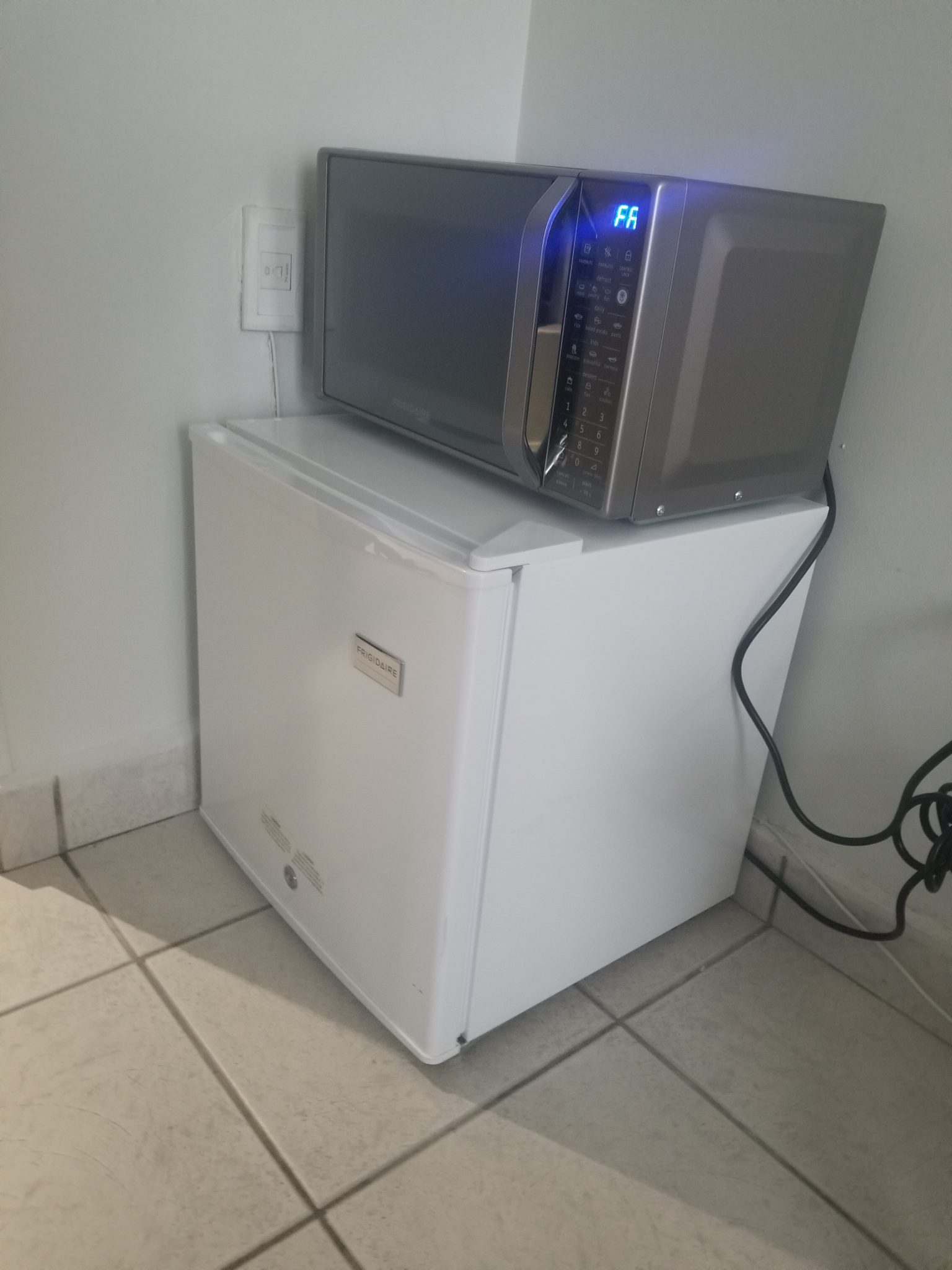 a microwave on top of a small refrigerator