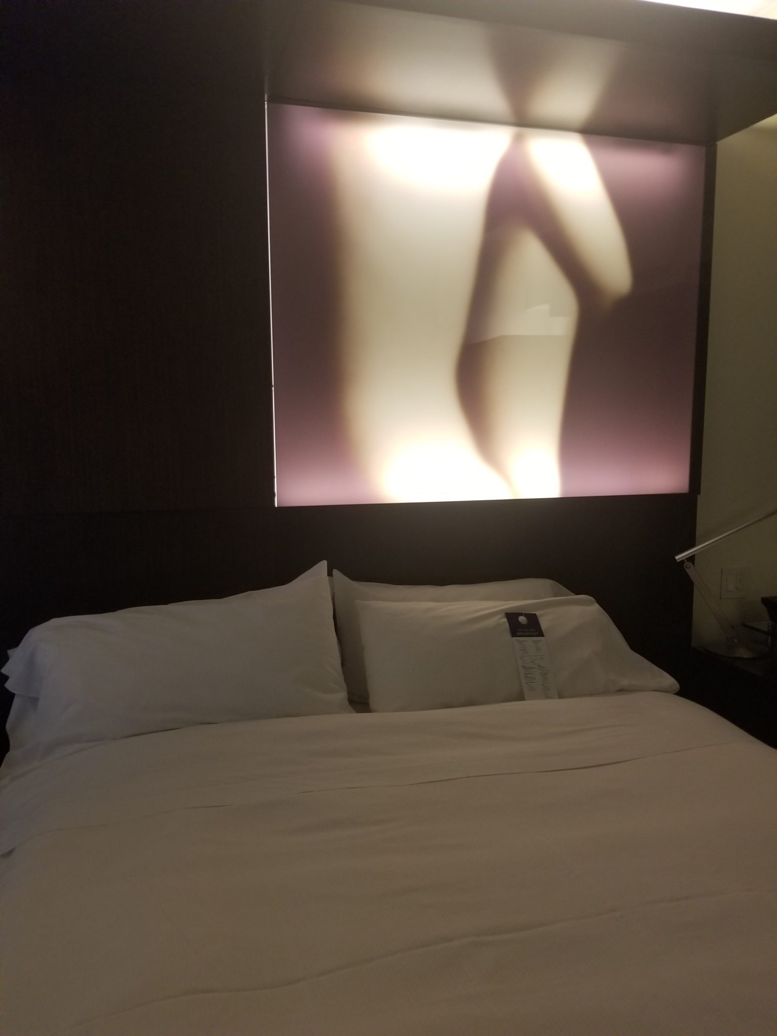 a bed with white sheets and a poster above it