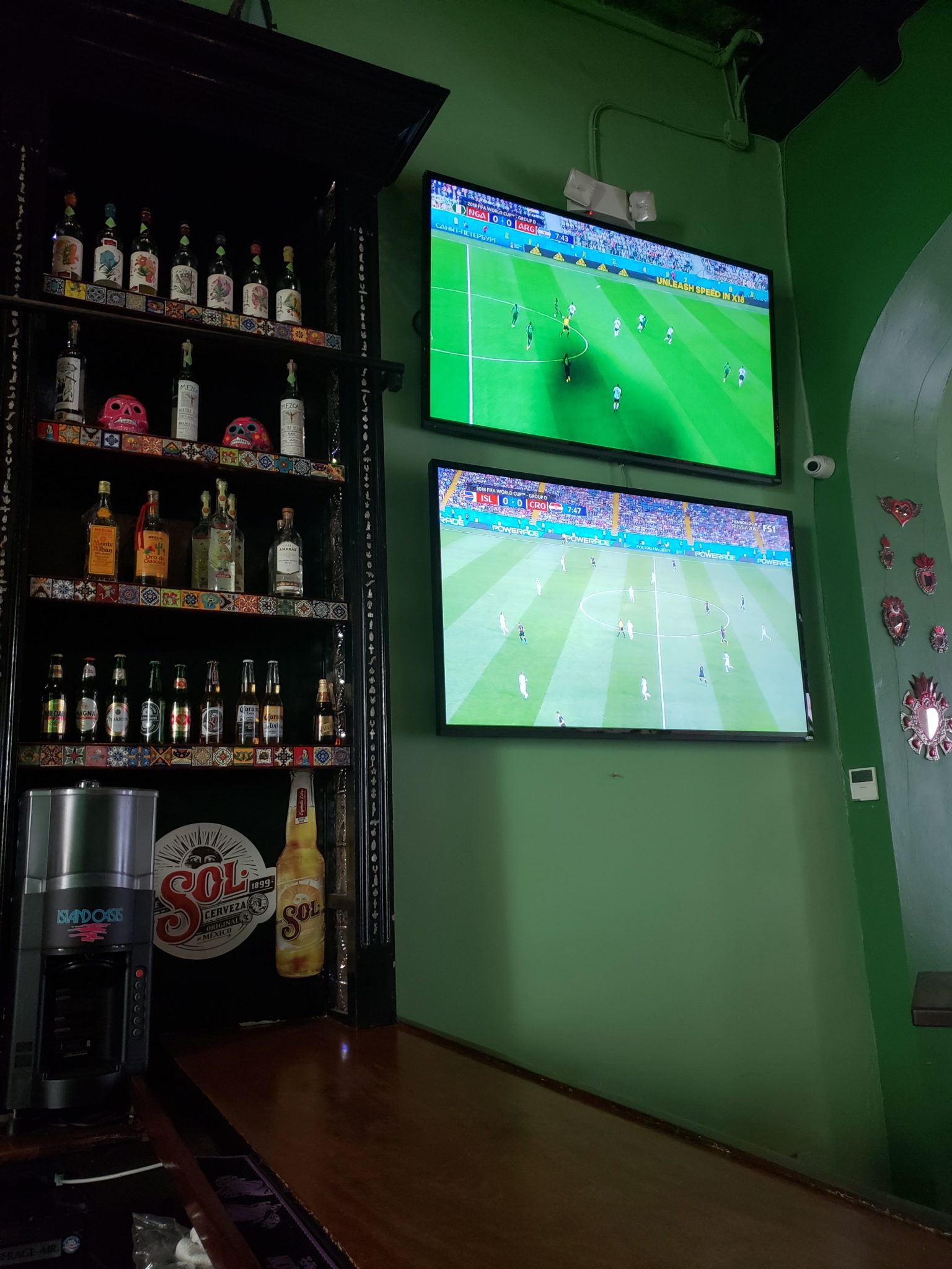 a tv and shelves with bottles on the wall