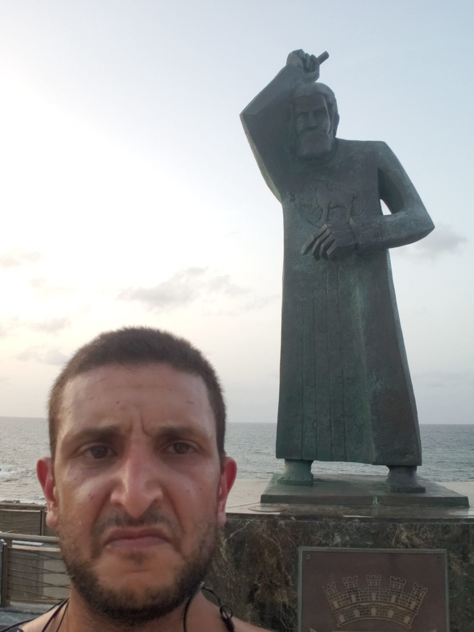 a man taking a selfie in front of a statue