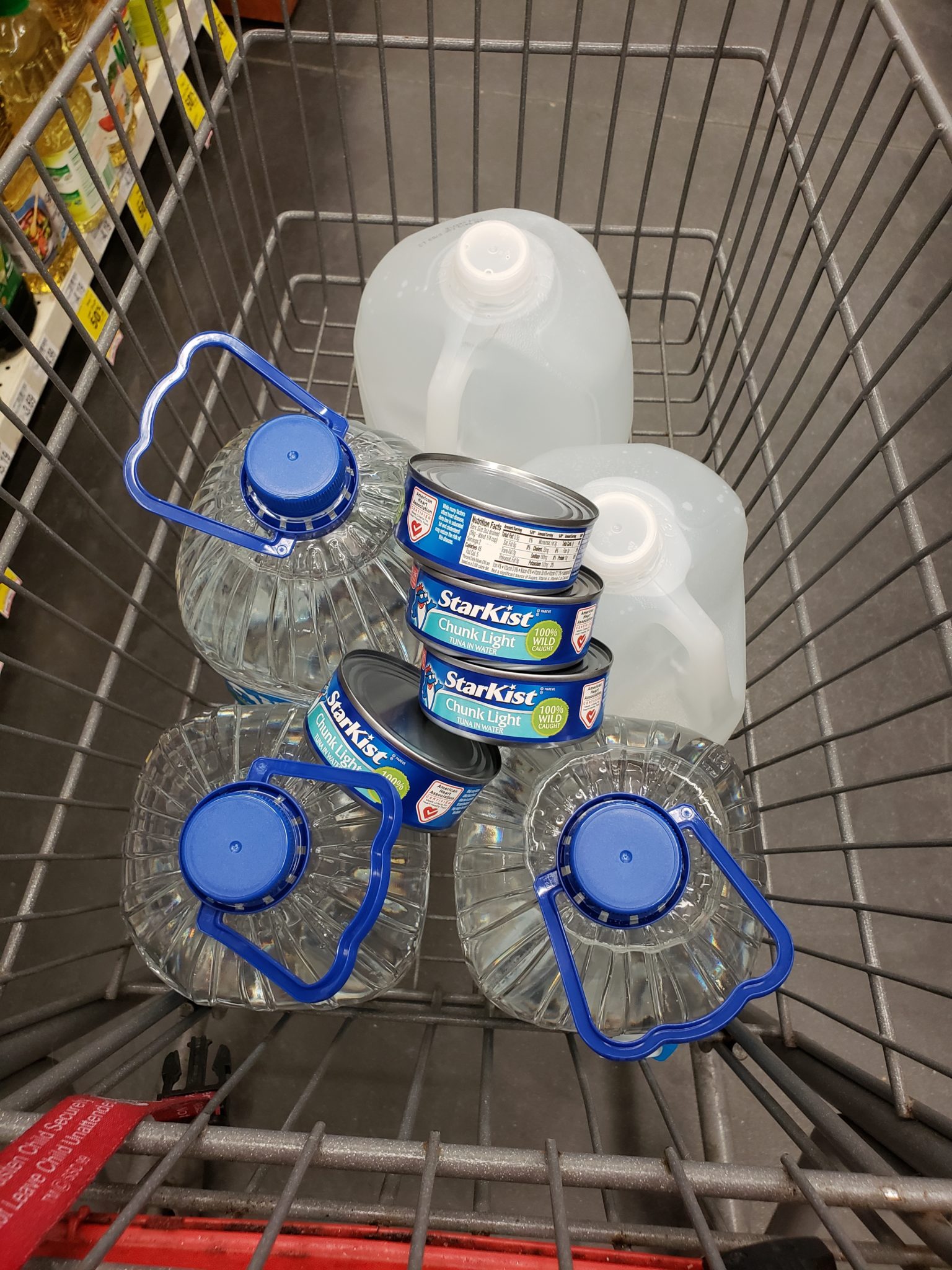 a shopping cart full of water bottles and cans