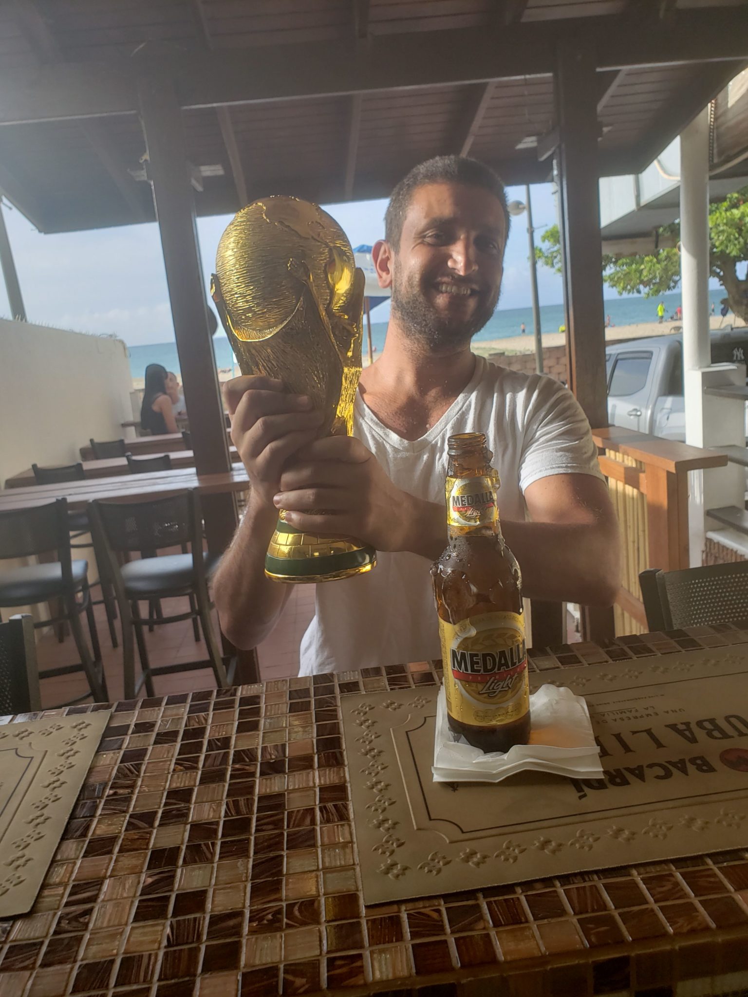 a man holding a trophy and a beer bottle