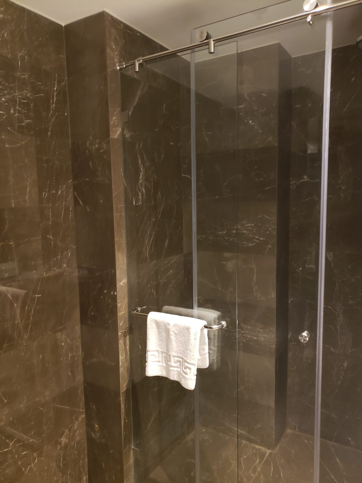 a glass shower with a towel on the glass door