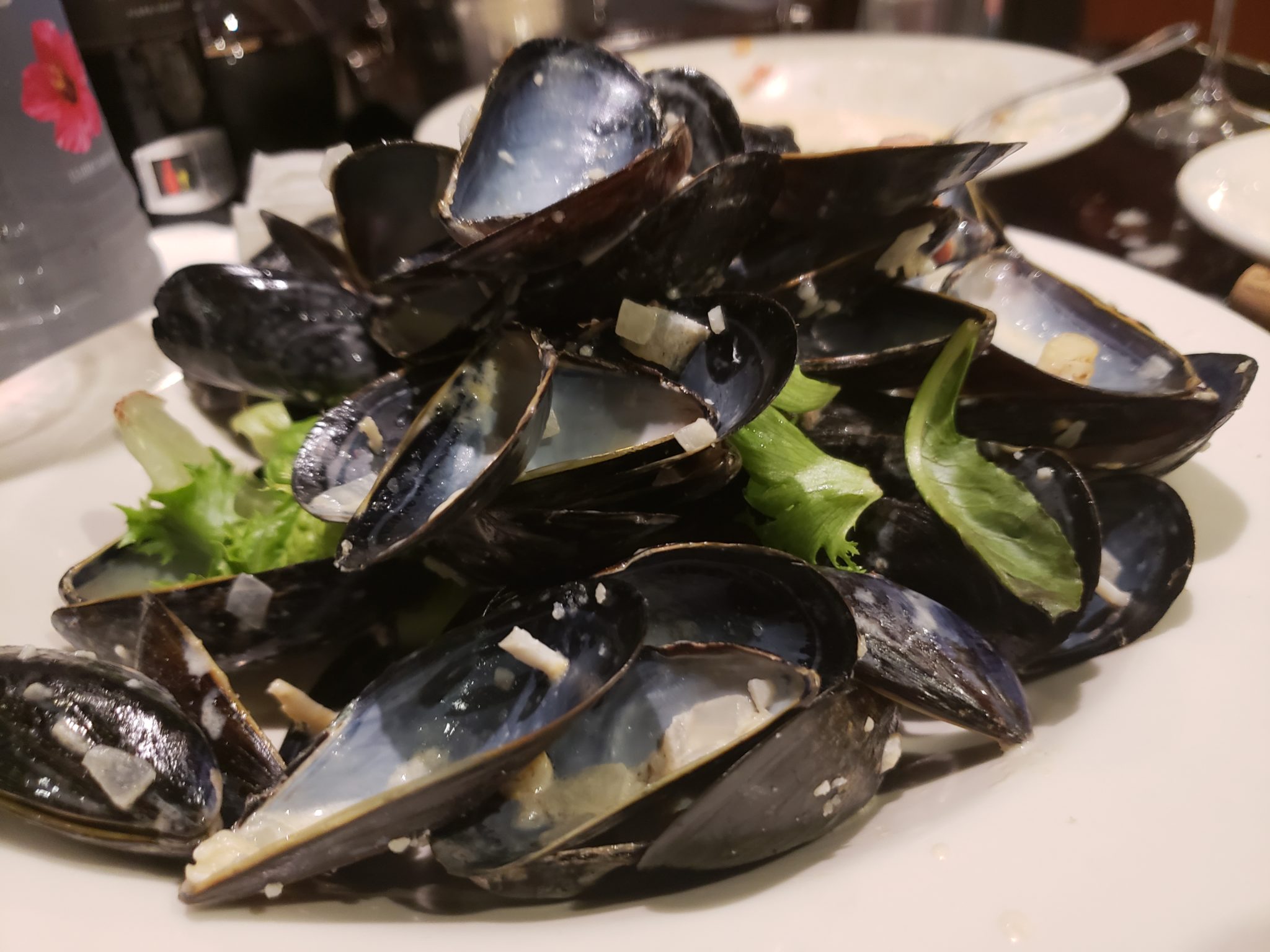 a plate of mussels with lettuce and onions