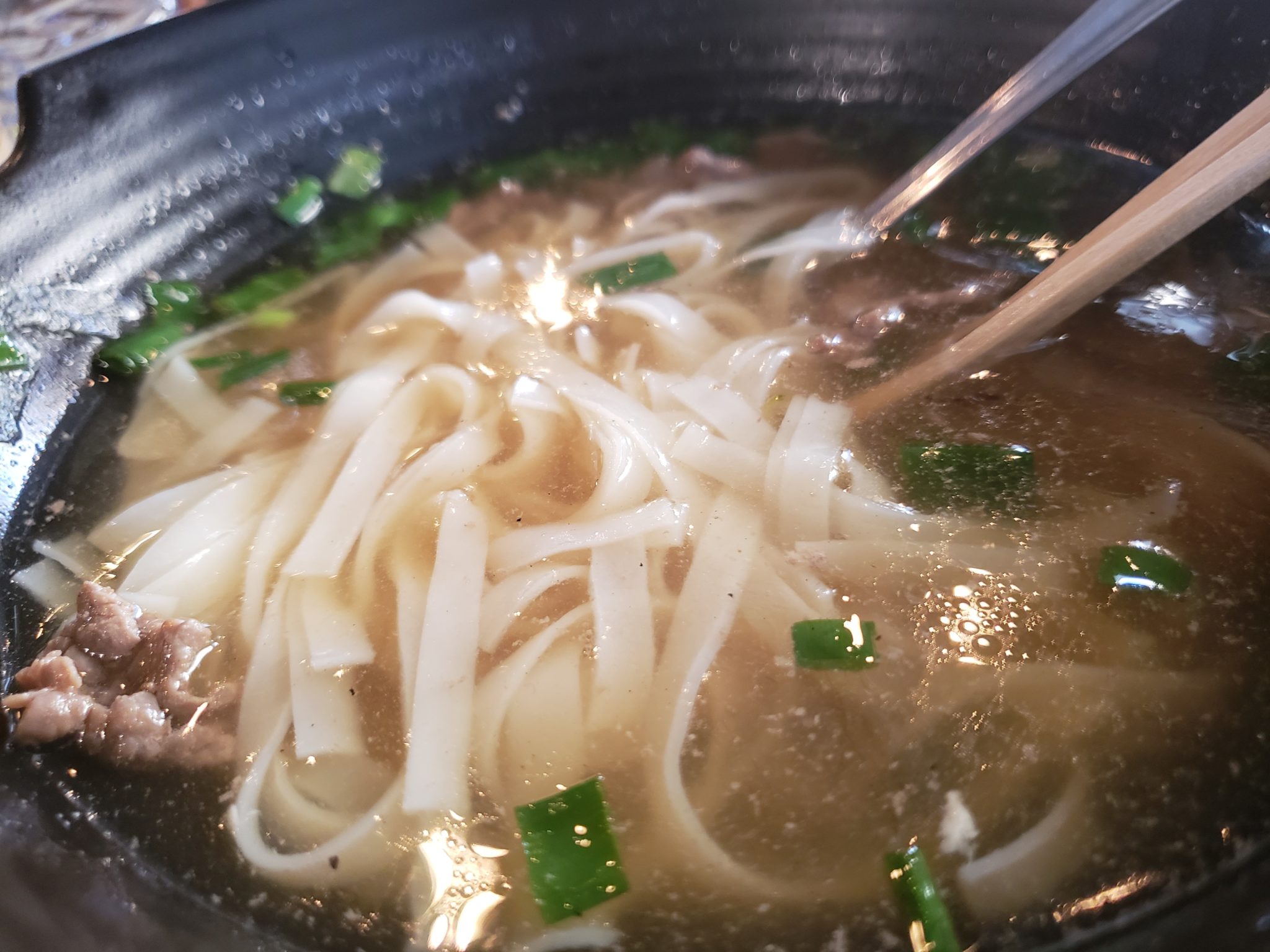a bowl of soup with noodles and chopsticks