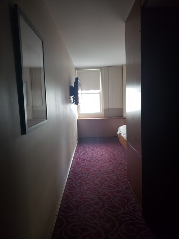a hallway with a bed and a window