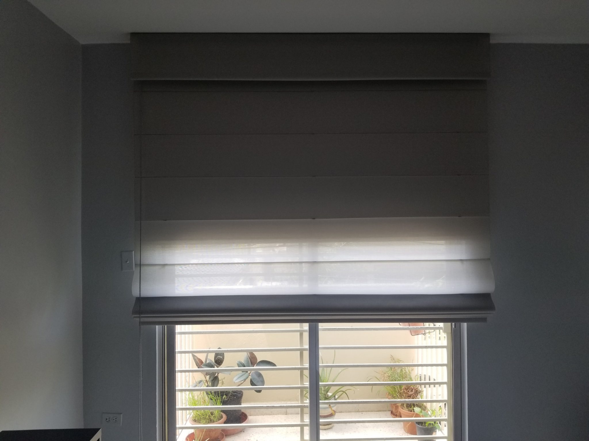 a window with blinds and a view of a patio