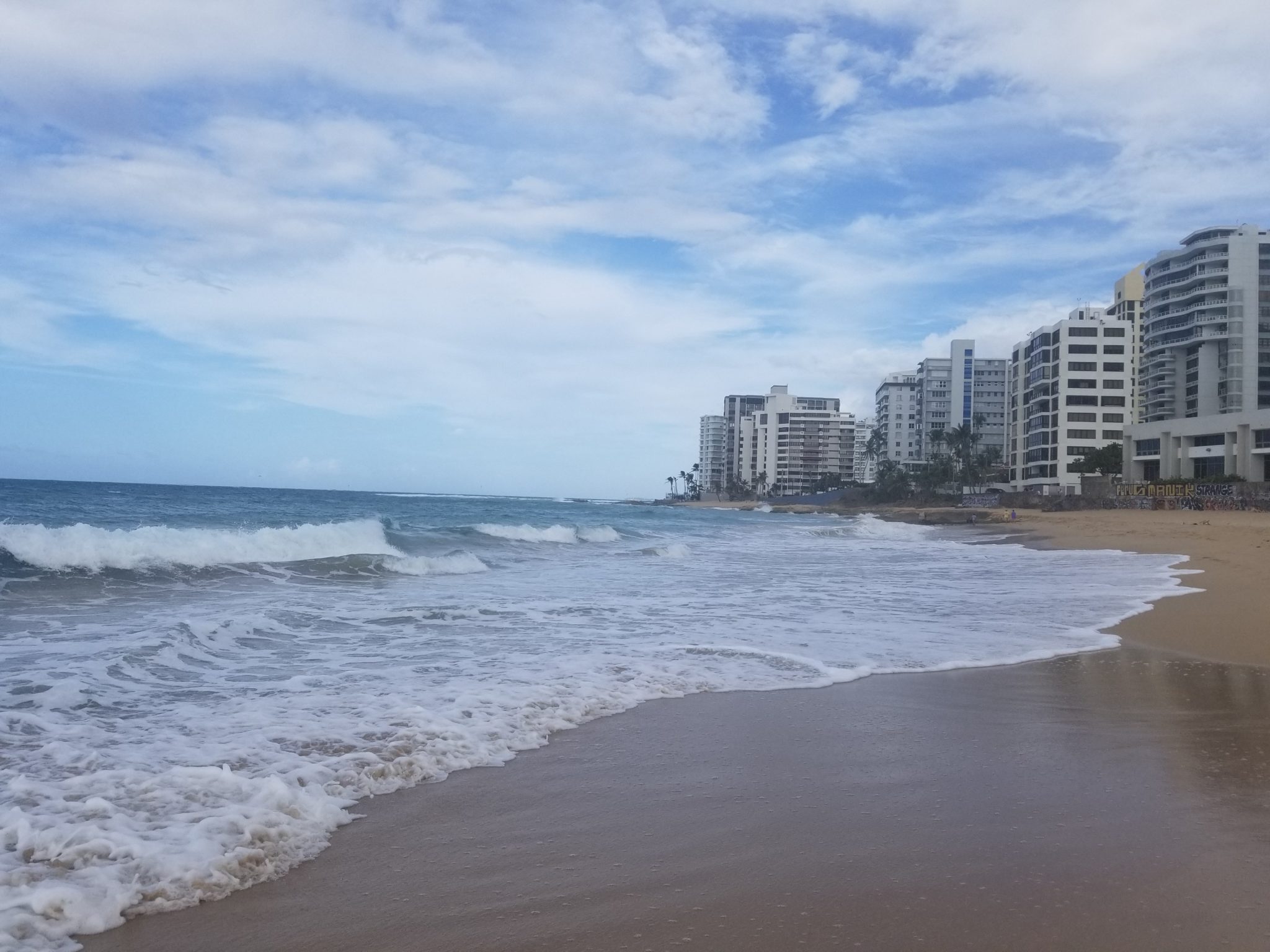 a beach with buildings and waves