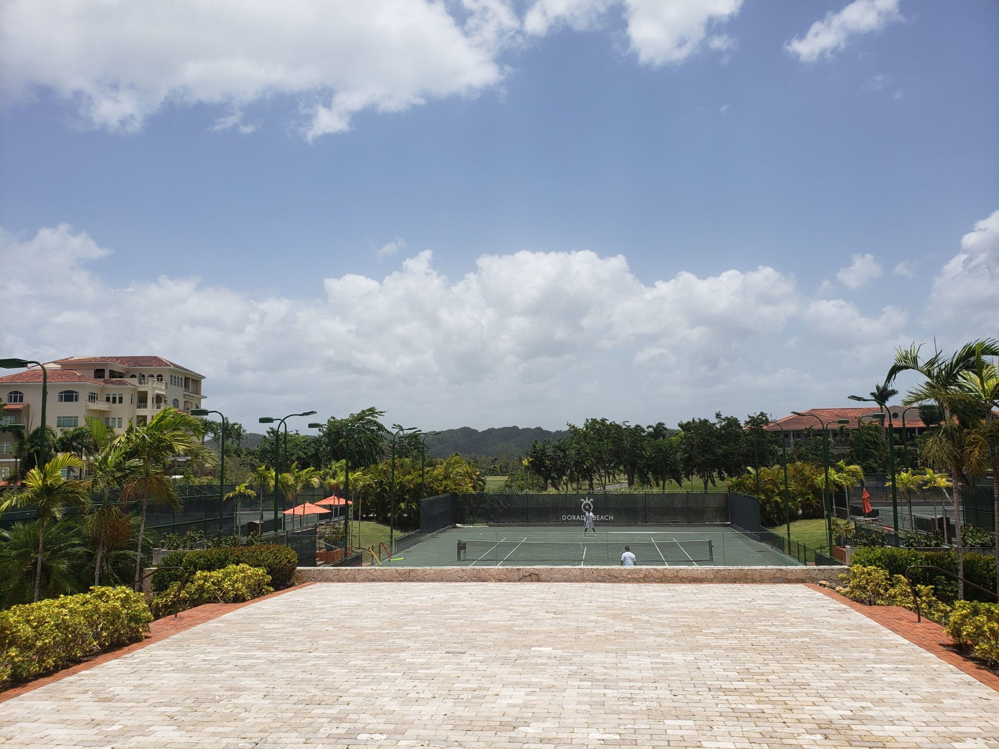 a tennis court with trees and buildings in the background