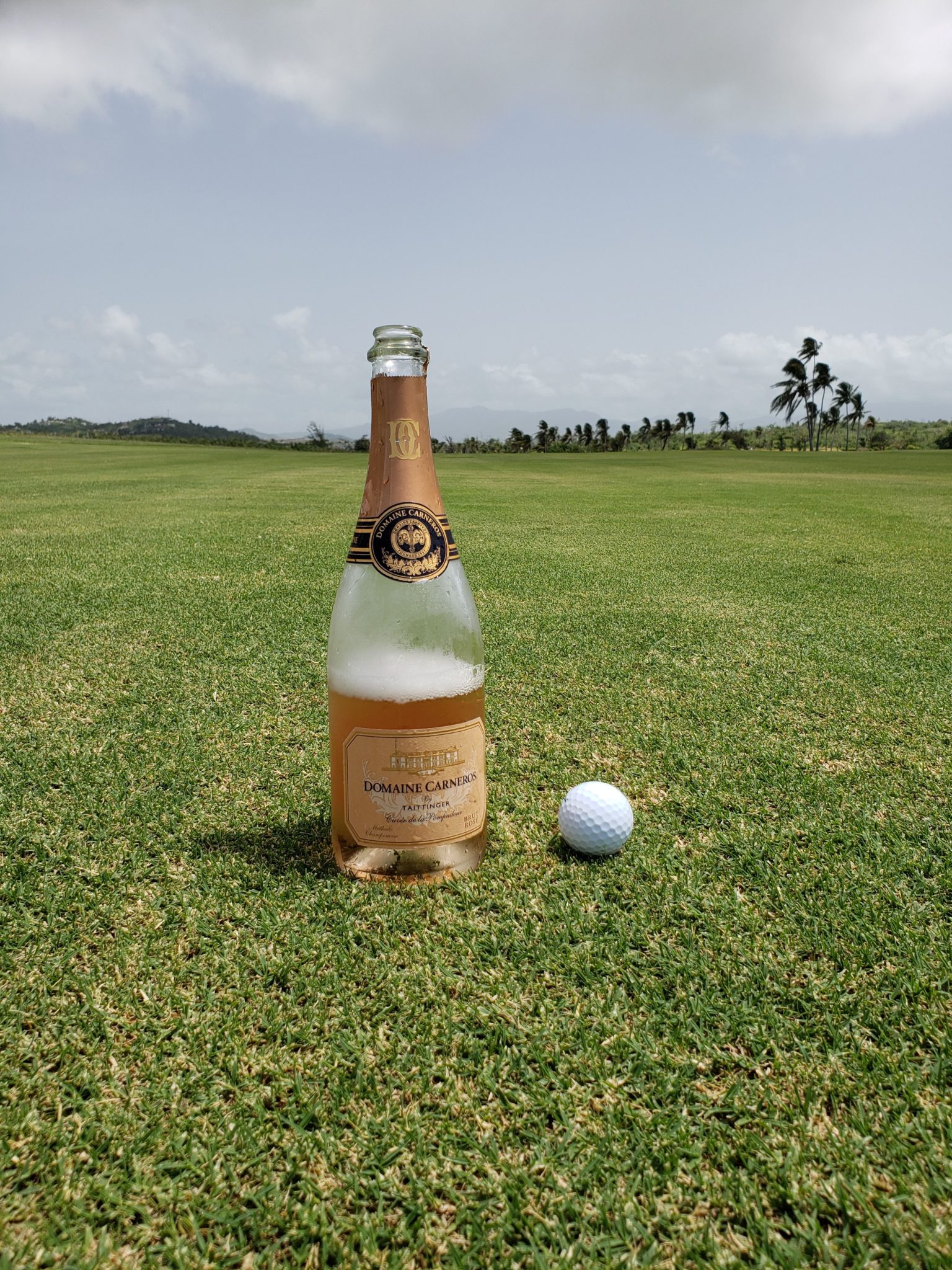 a bottle of champagne and a golf ball on a golf course
