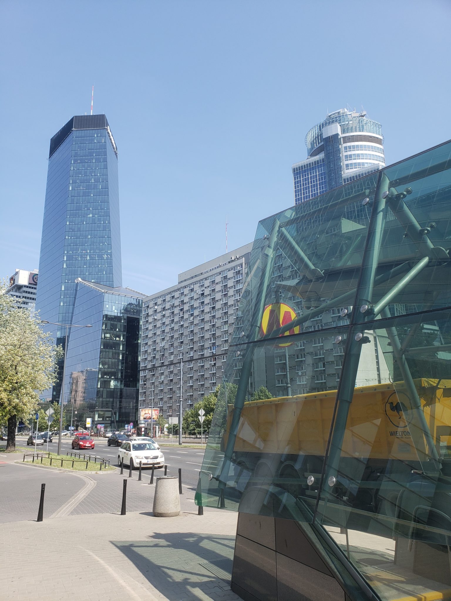 a glass building with a yellow truck in front of a city street