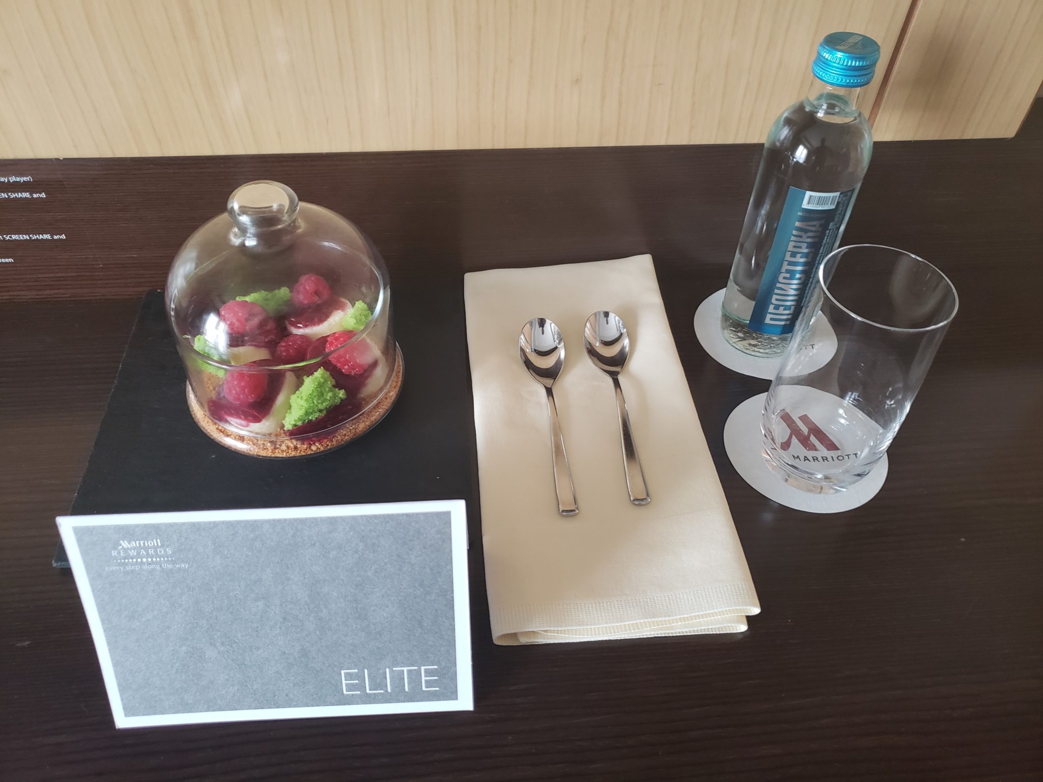 a table with a glass and spoons and a bottle of water