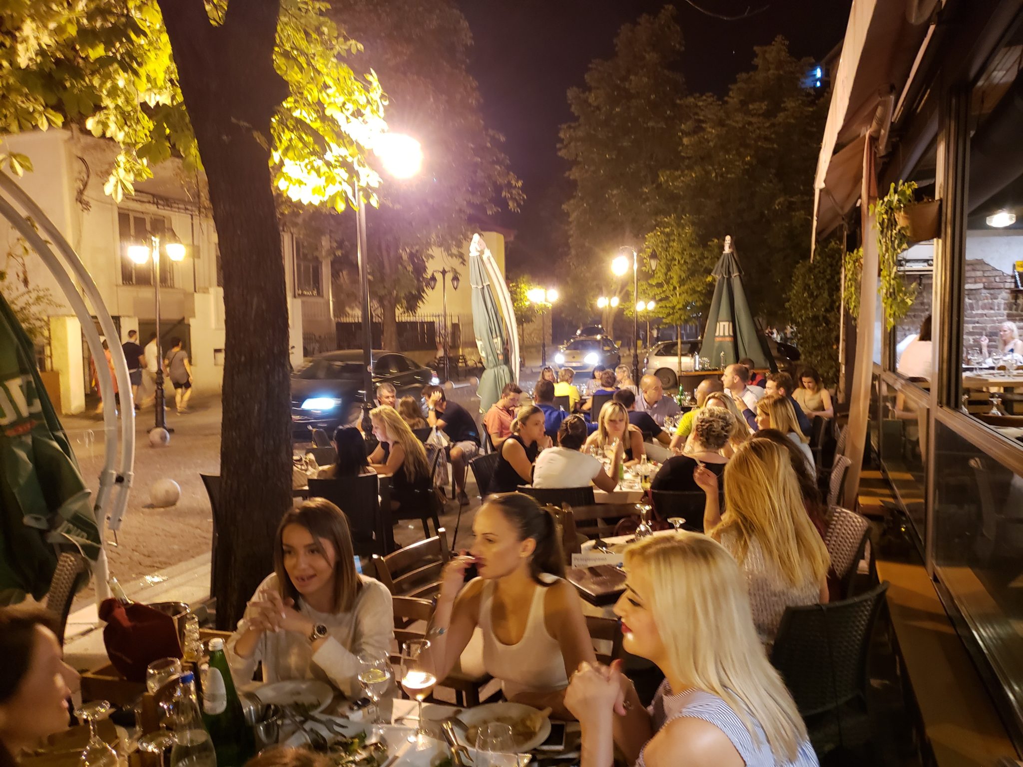 a group of people sitting at tables outside at night