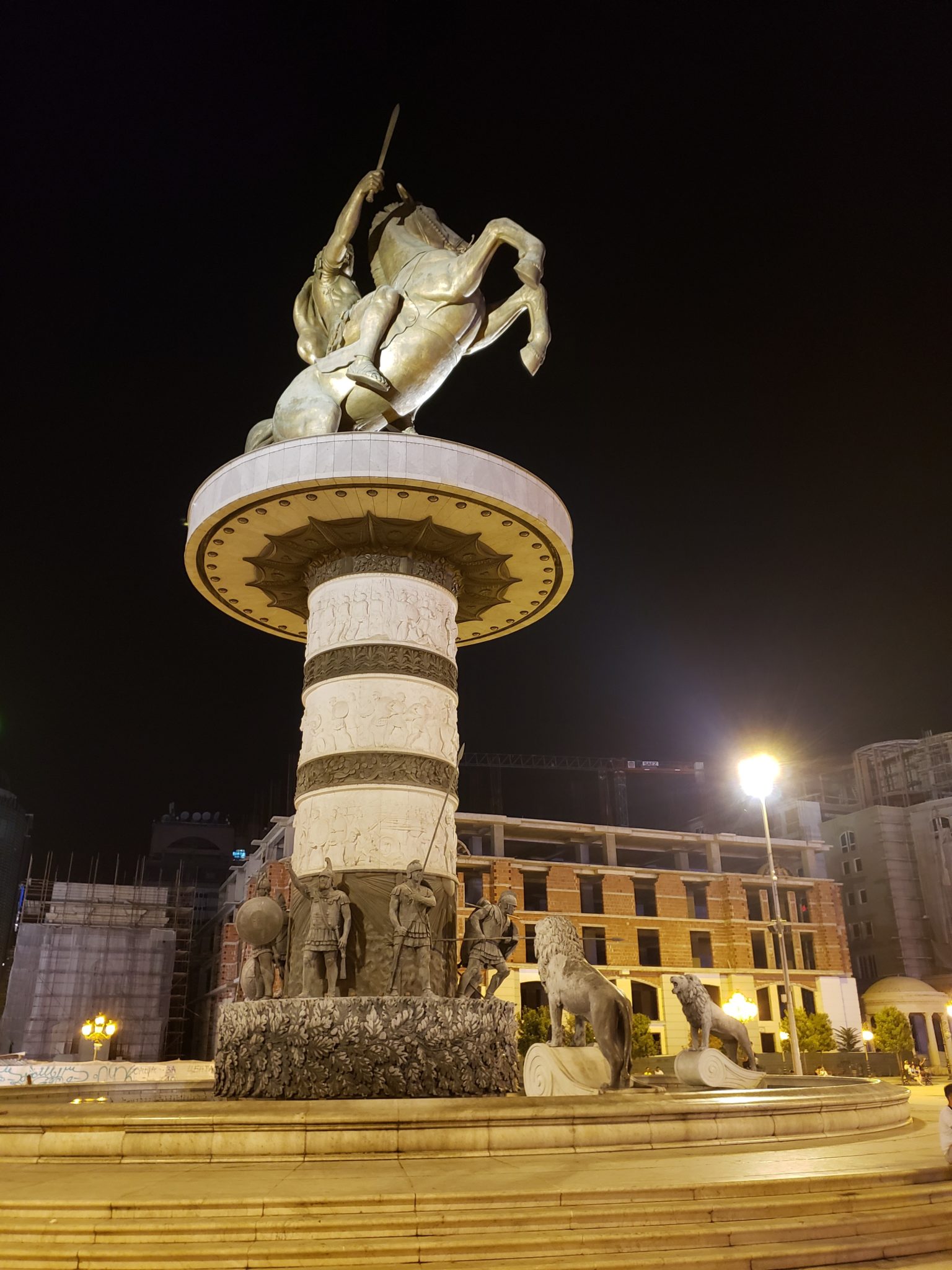 a statue of a man riding a horse on a pedestal in a city