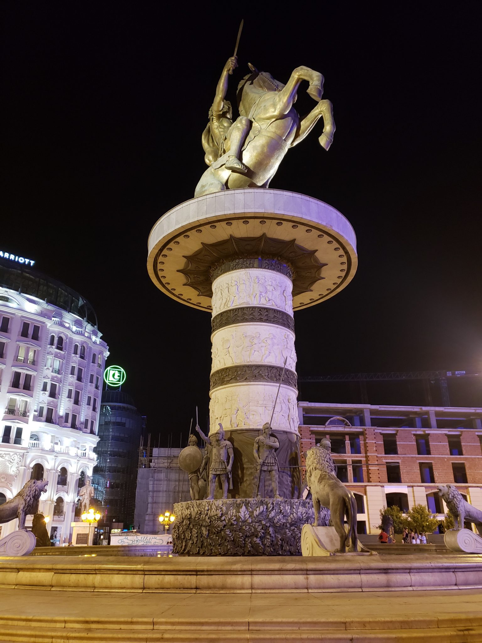 a statue of a man riding a horse on a pedestal in a city