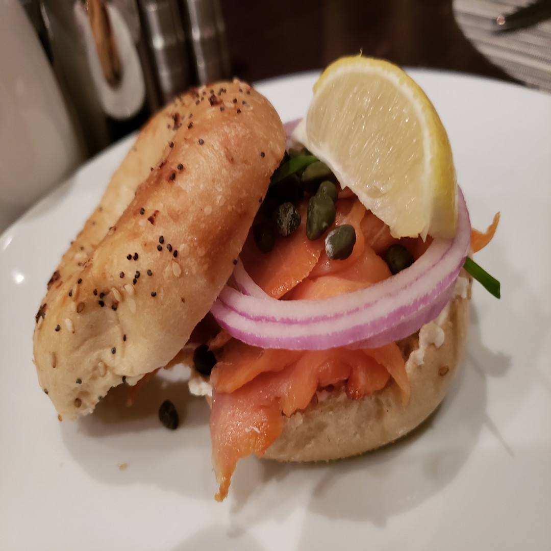 a bagel with salmon and onions on a white plate