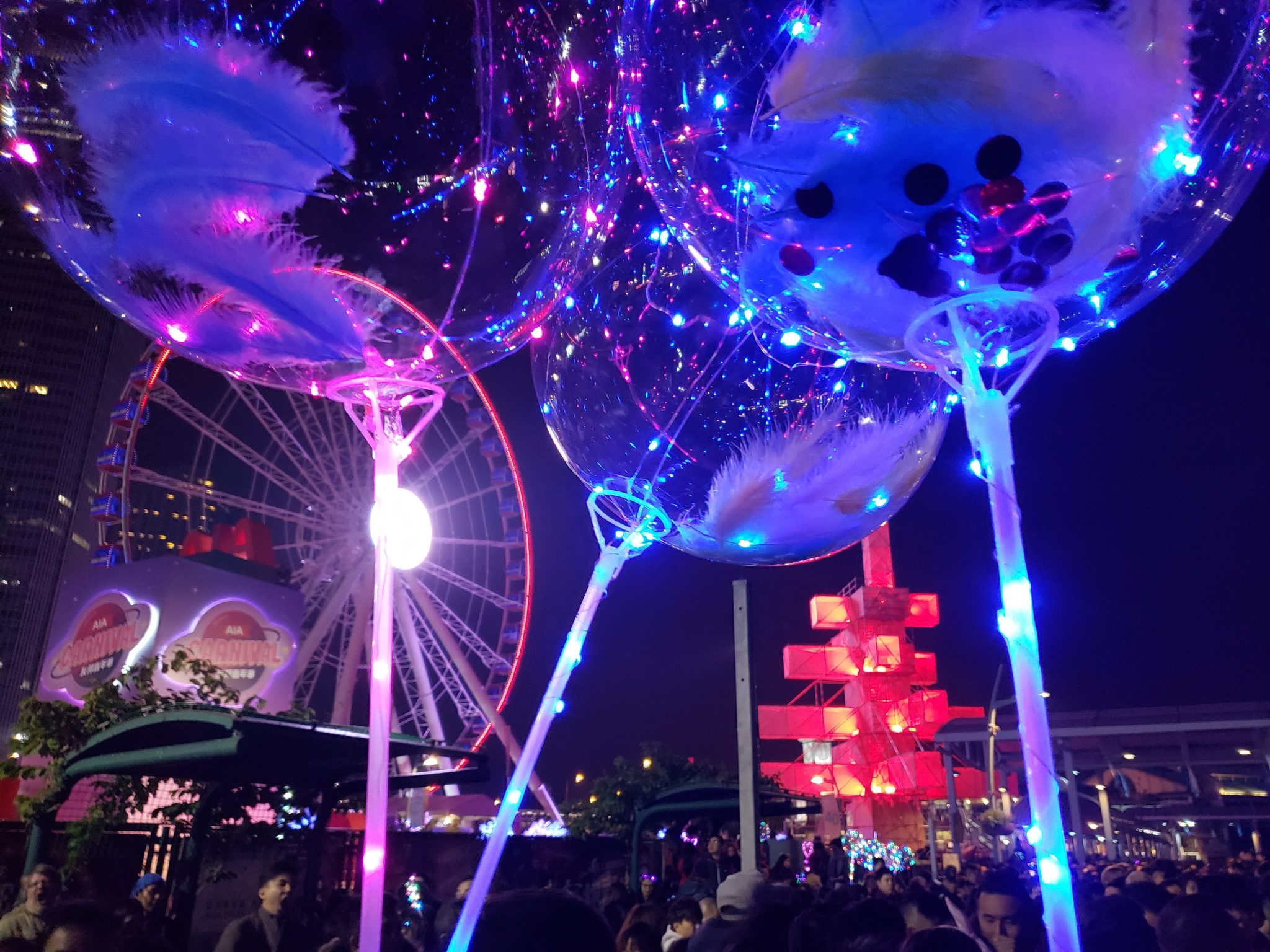 a group of balloons with lights and a ferris wheel at night