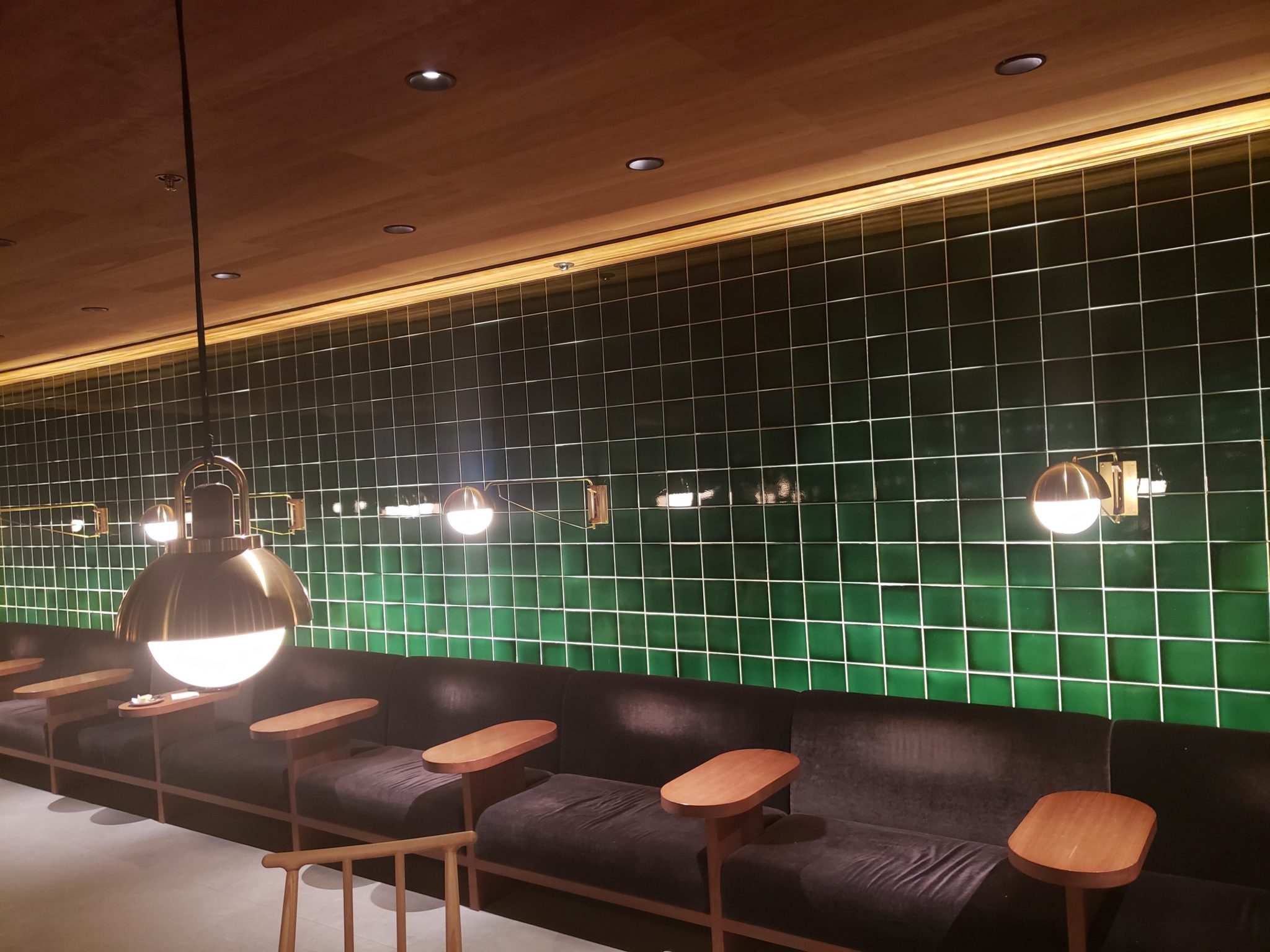 a green tile wall with a couch and chairs