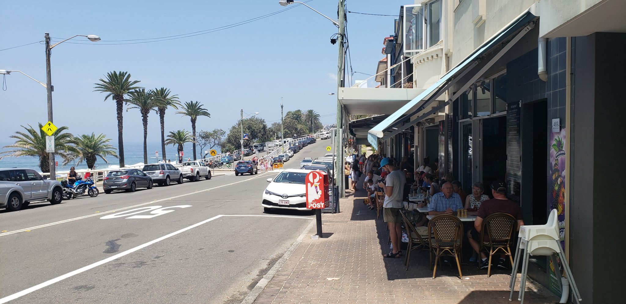 a street with cars and people sitting at tables
