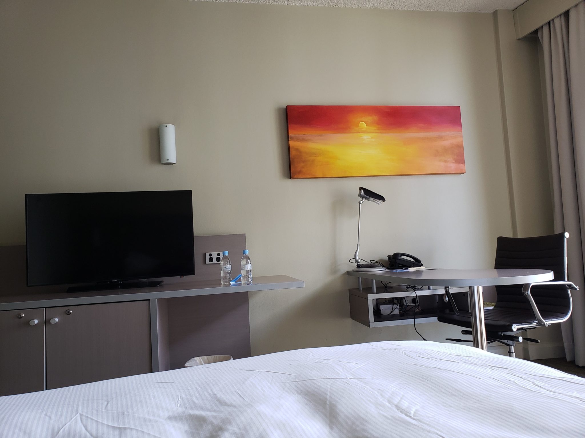 a room with a bed and a desk and a painting on the wall