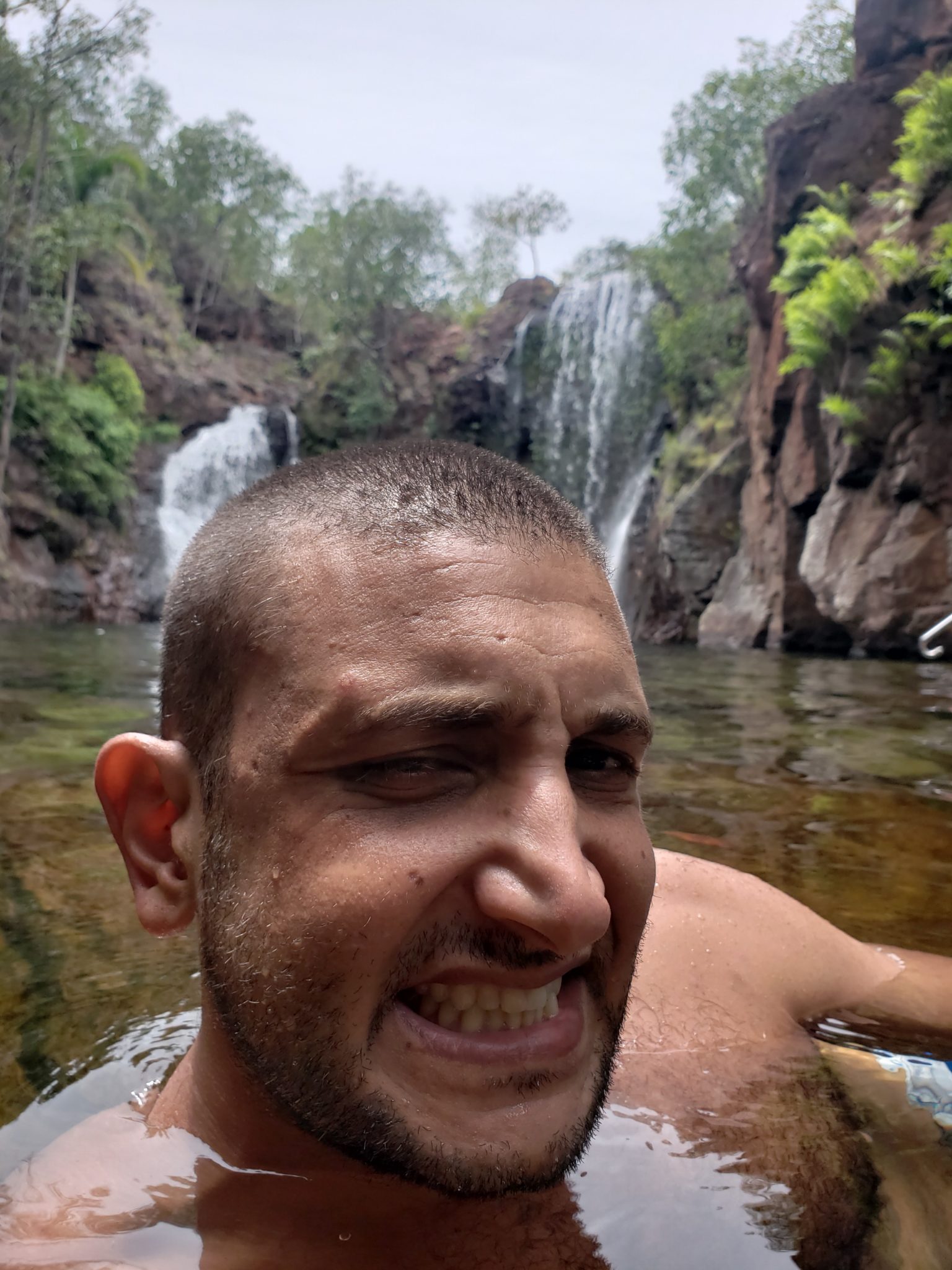 a man in a river with a waterfall in the background