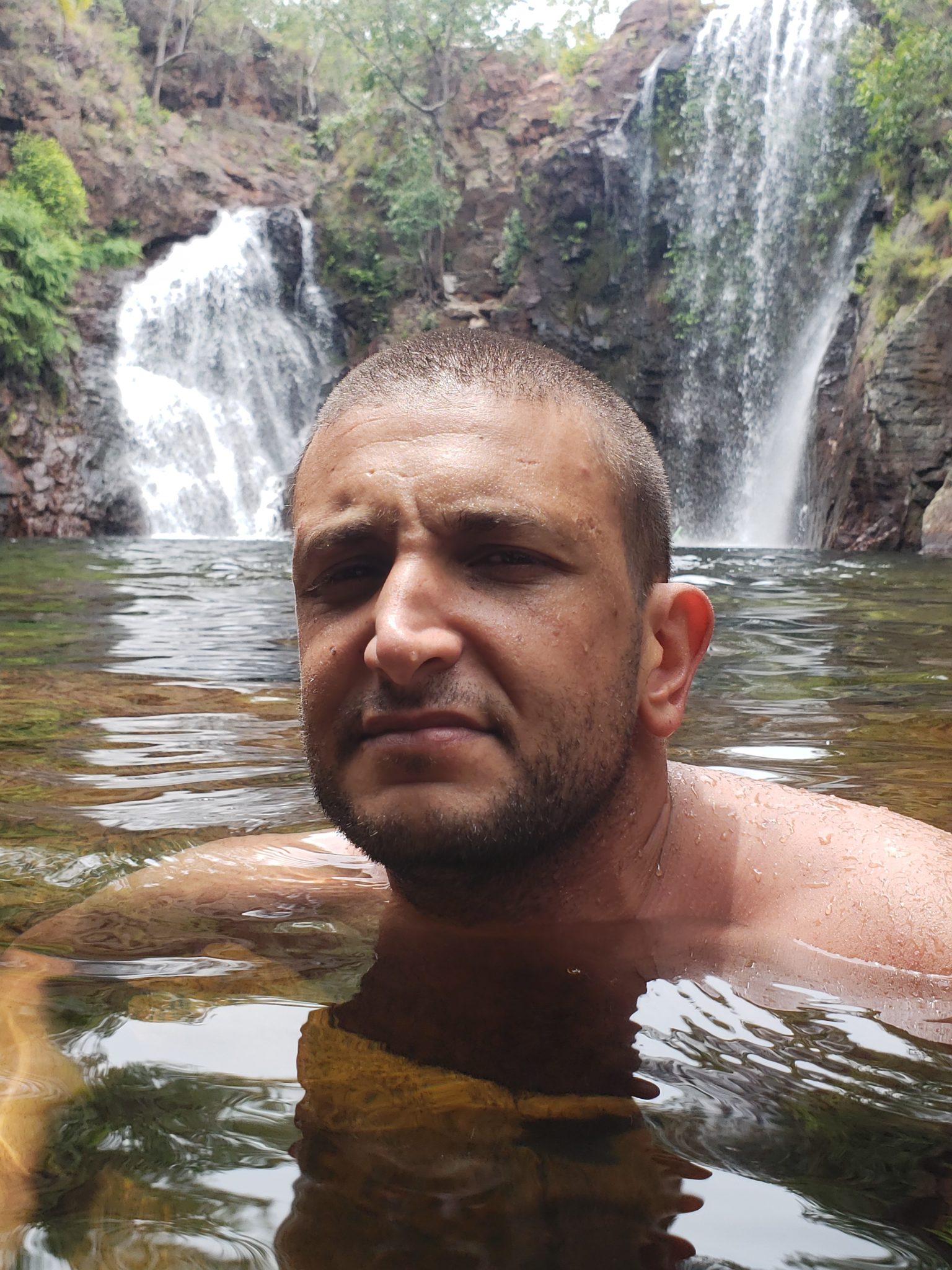 a man in water with a waterfall in the background