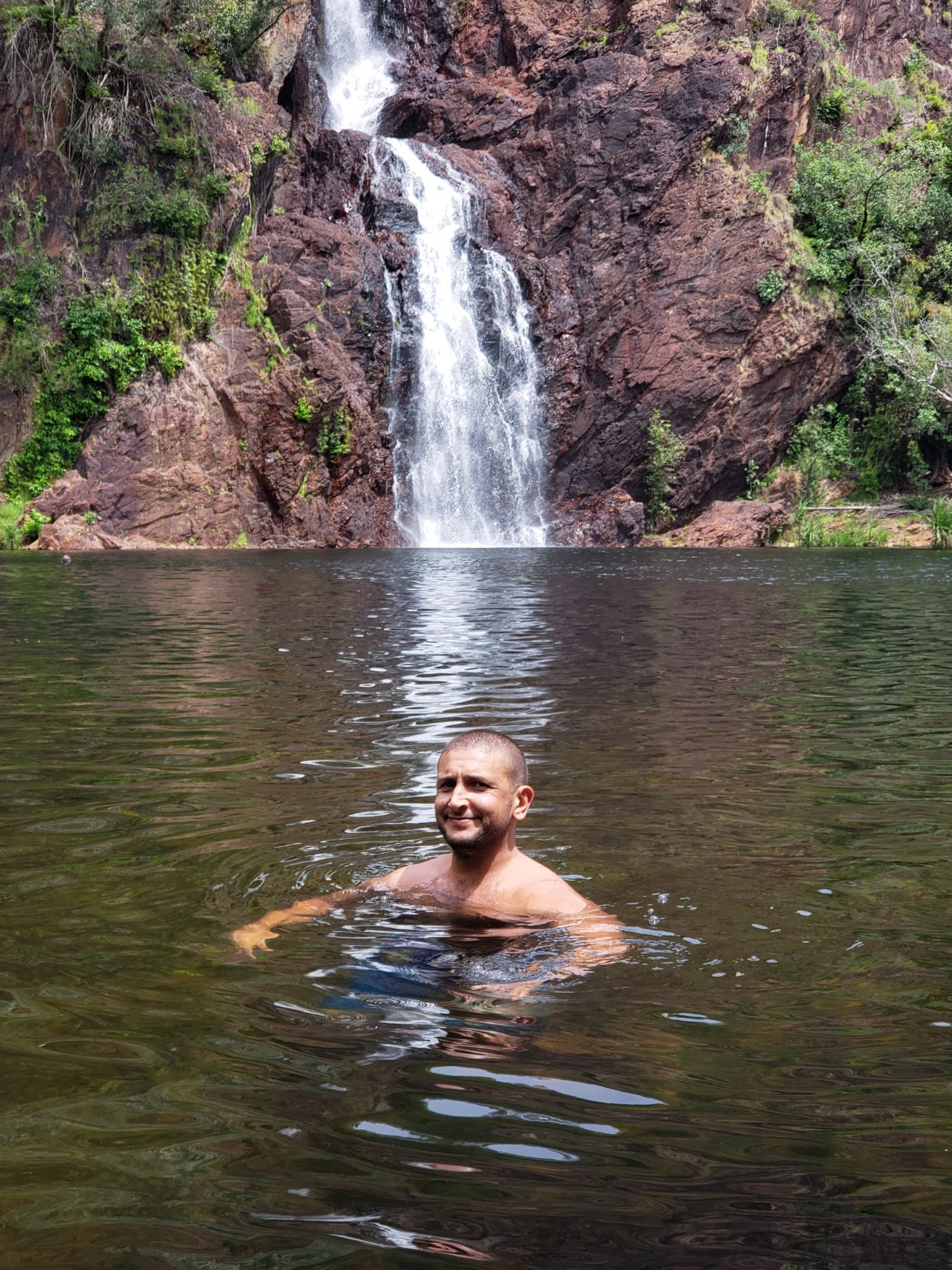 a man in a lake with a waterfall in the background