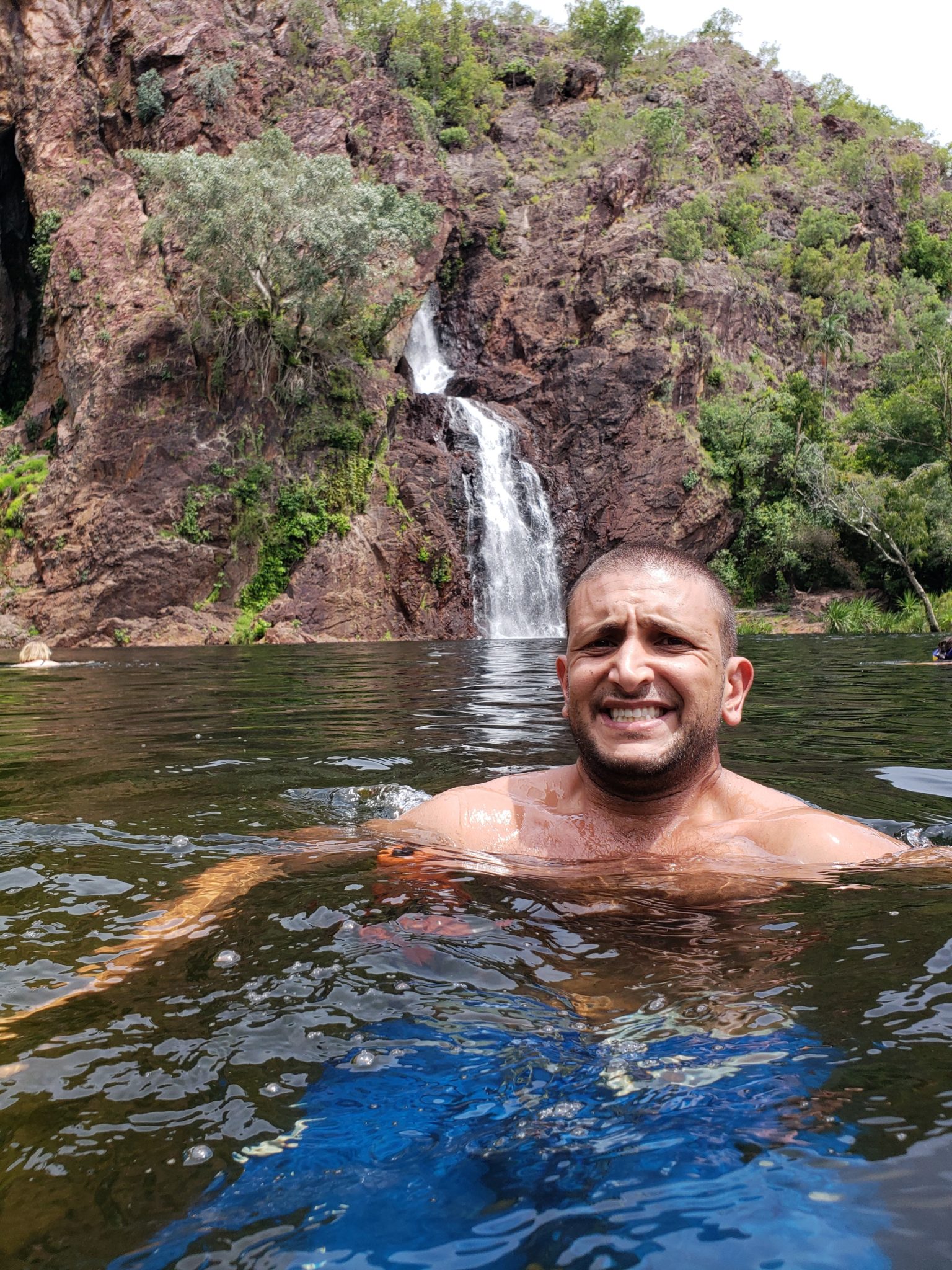 a man in a body of water with a waterfall in the background