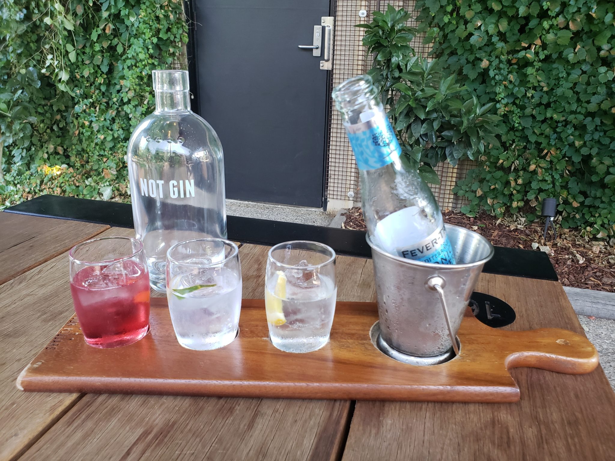a group of glasses and a bottle on a wooden tray
