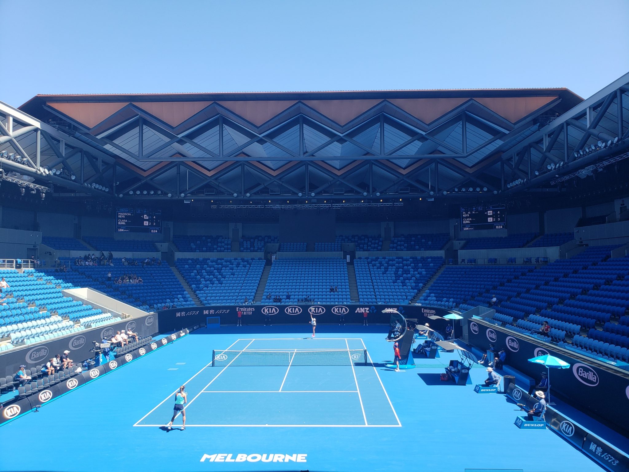 a tennis court with blue seats and blue roof