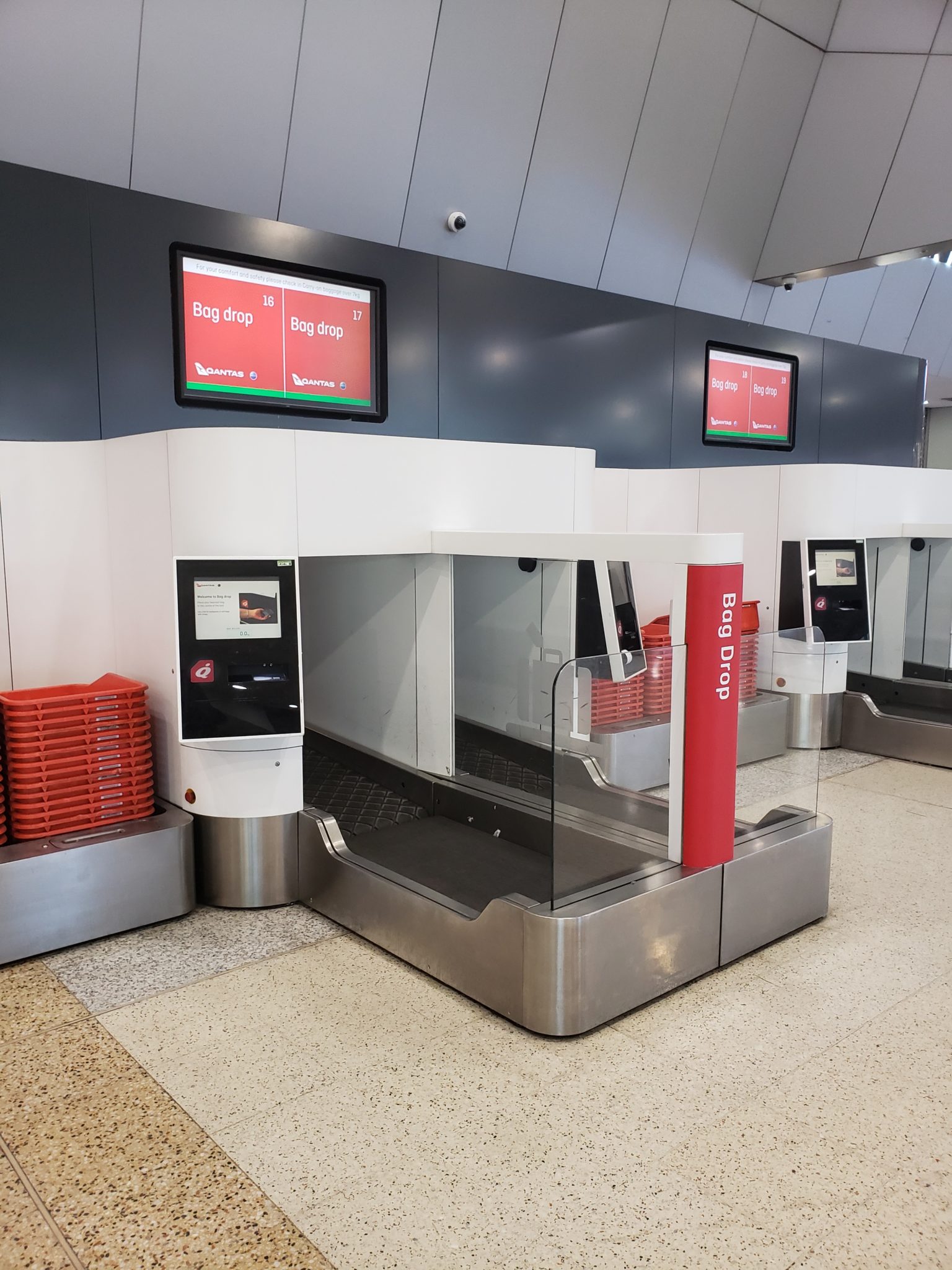 a airport check-in area with a screen and a sign