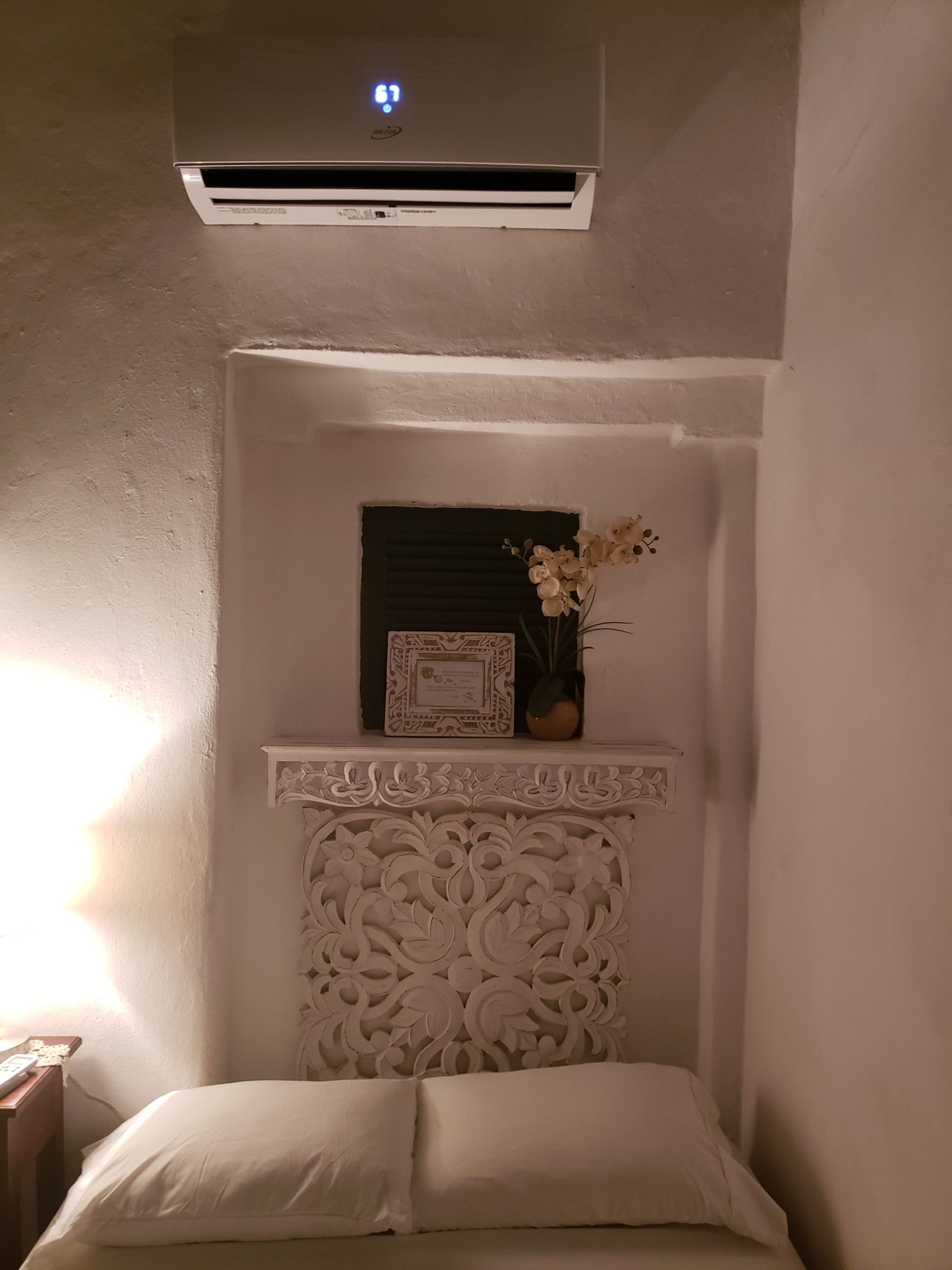 a white wall with a shelf and a air conditioner