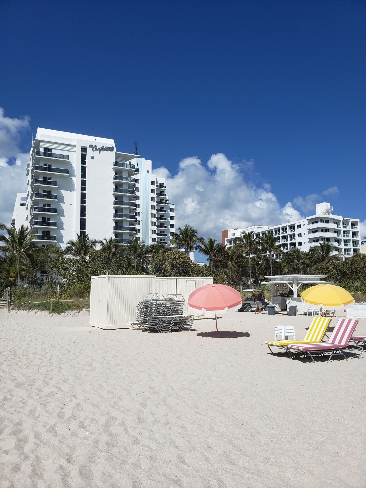 a beach with chairs and umbrellas and buildings
