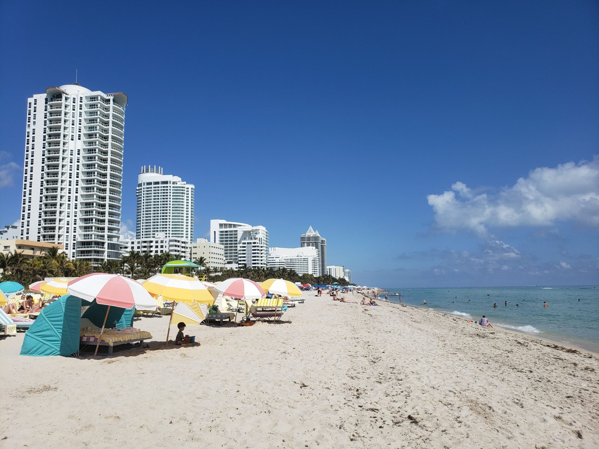 a beach with umbrellas and buildings in the background