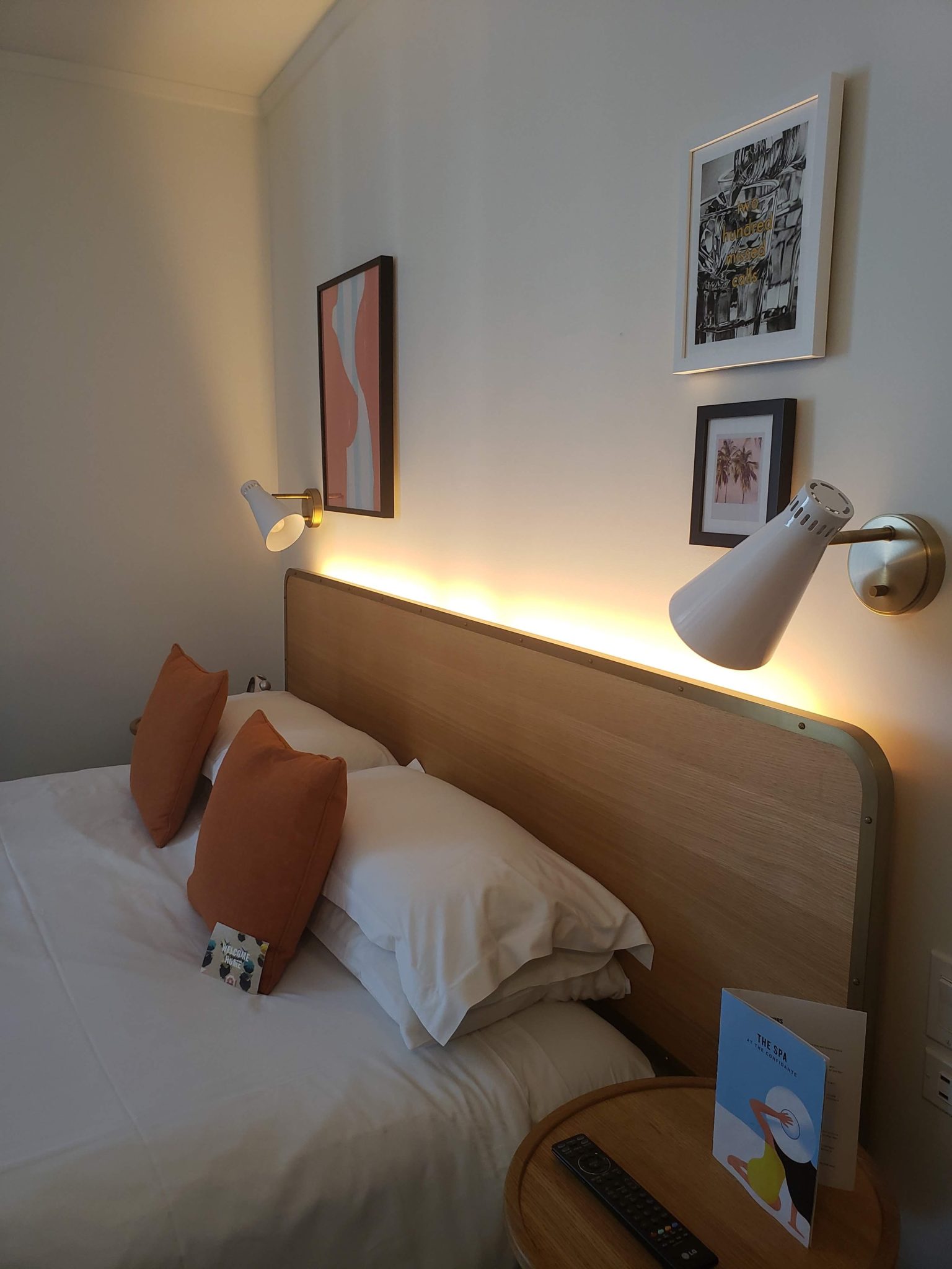 a bed with pillows and a lamp on the wall