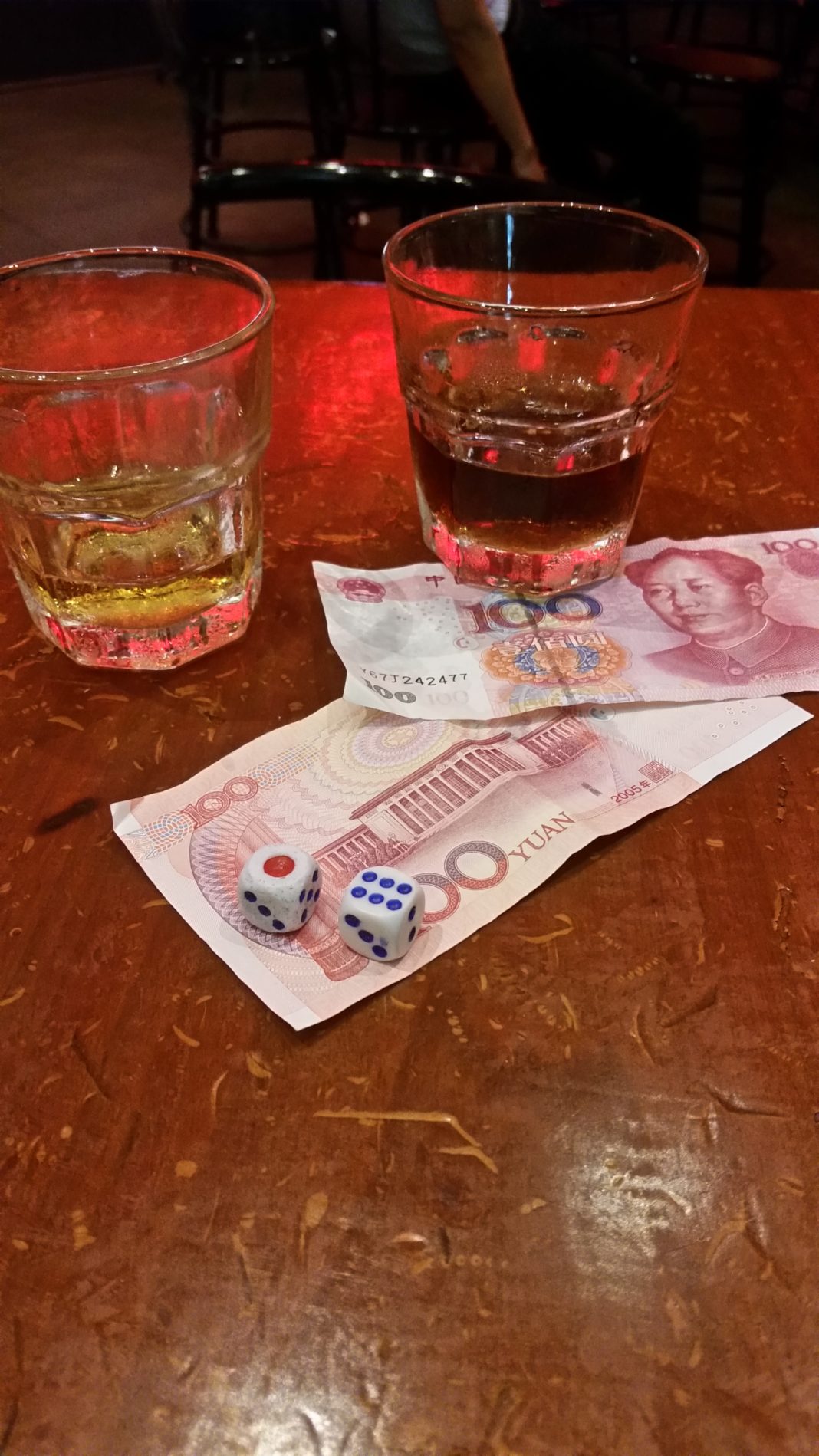two glasses of alcohol and dice on a table